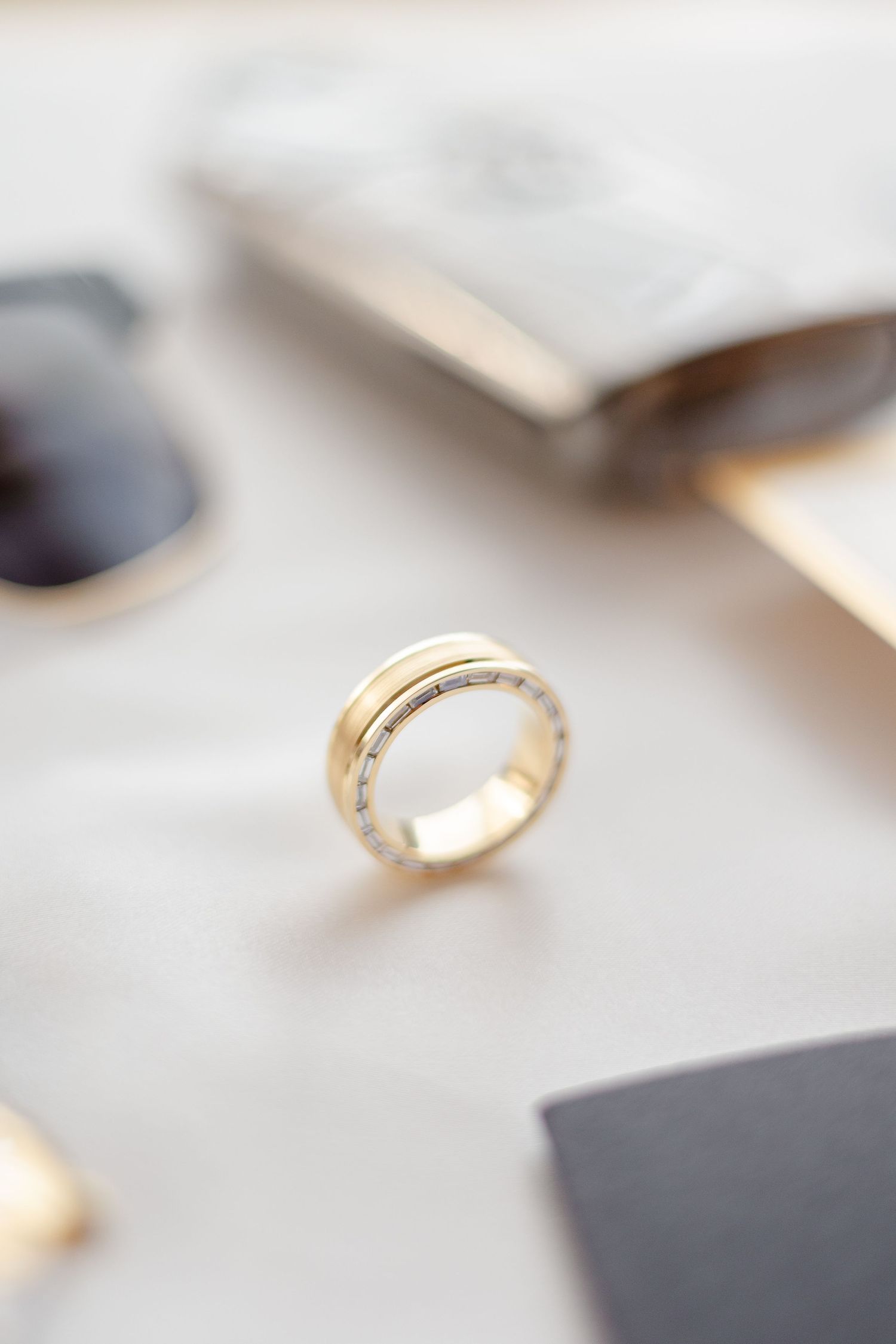 Close-up of a gold wedding band with intricate details against a light background.