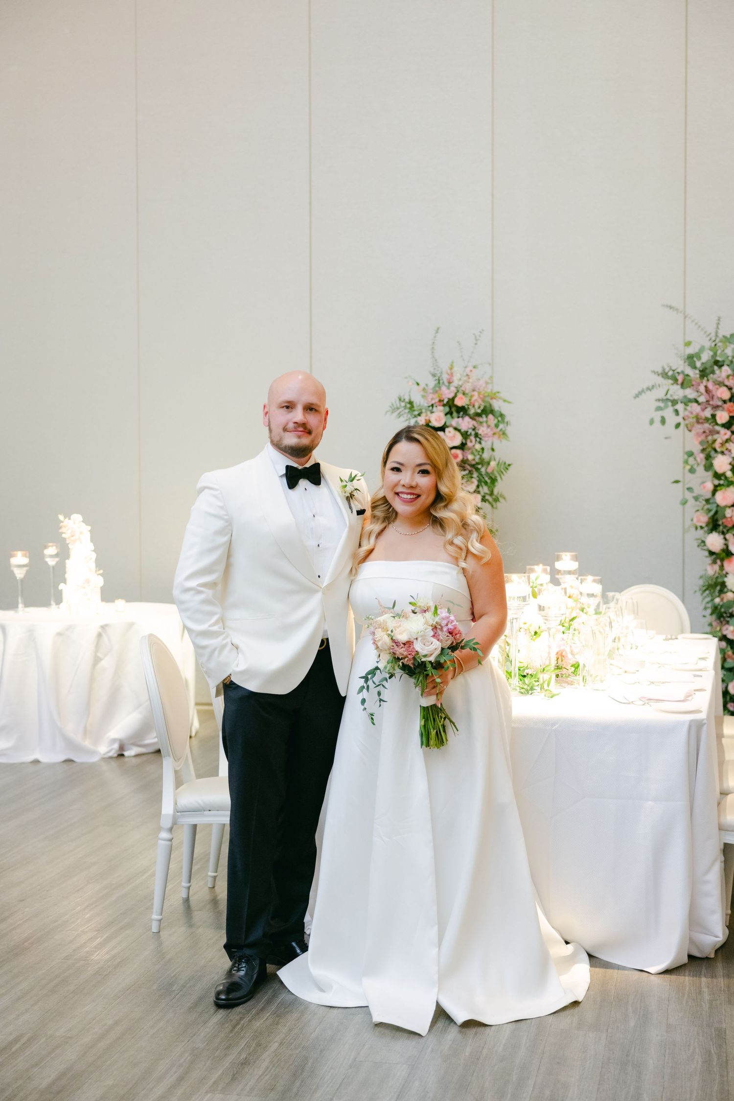Wedding couple posing in front of elegant floral arrangements in modern venue.