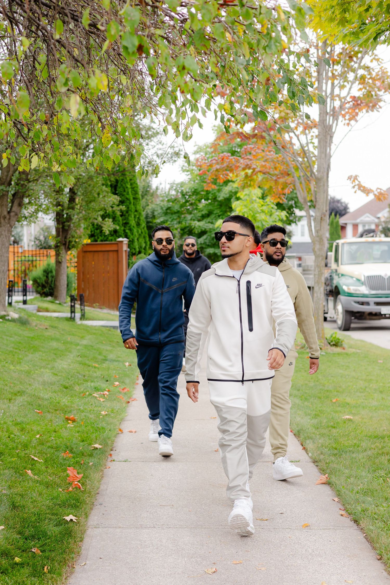 A group walks along an autumn sidewalk in coordinated athletic wear.