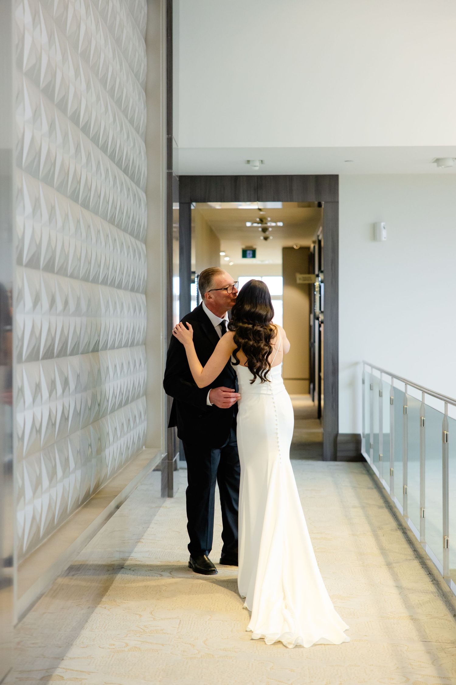 Emotional moment captured in a modern hallway with textured wall details.