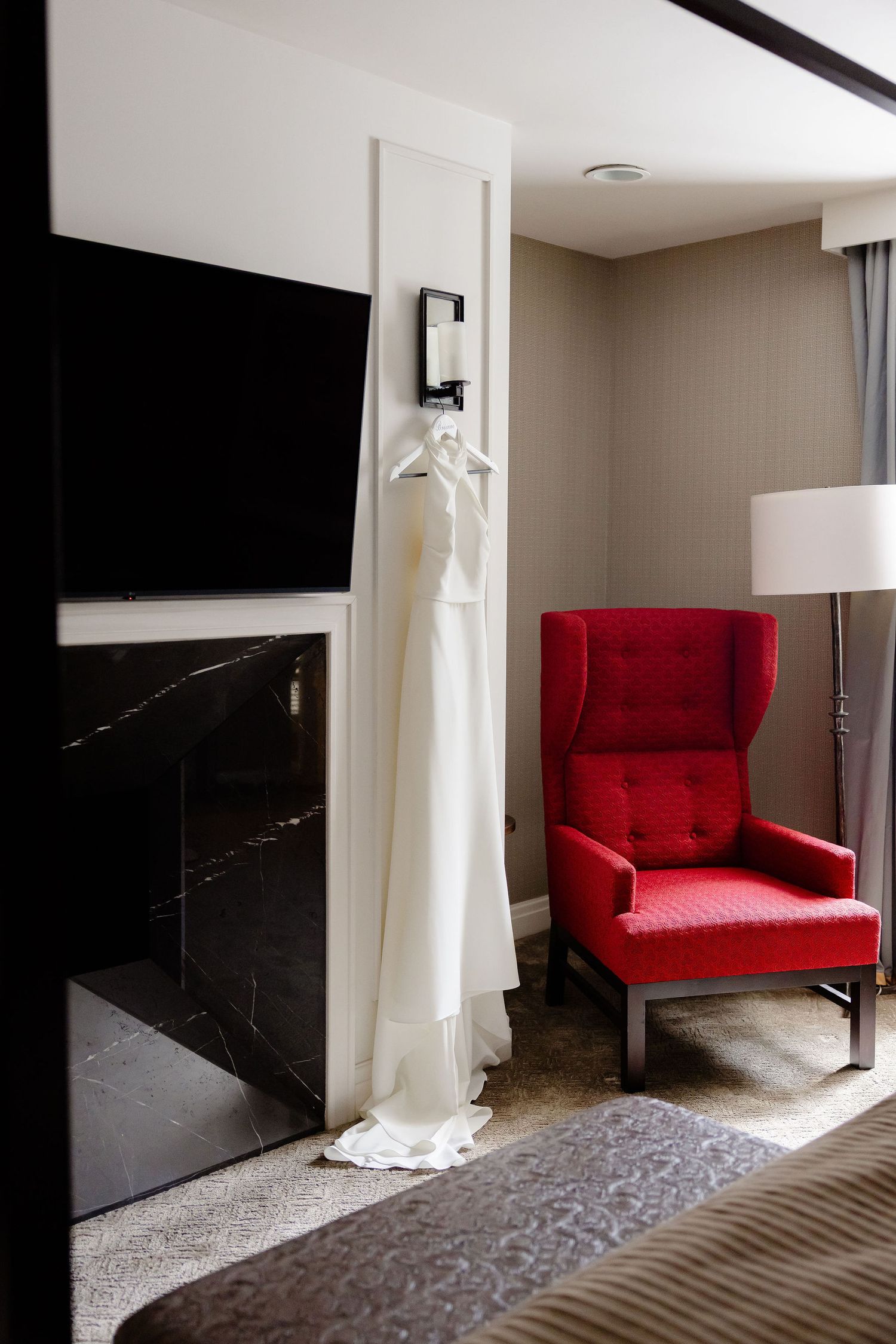 Modern bedroom interior featuring a bold red accent chair against neutral walls and carpeting.