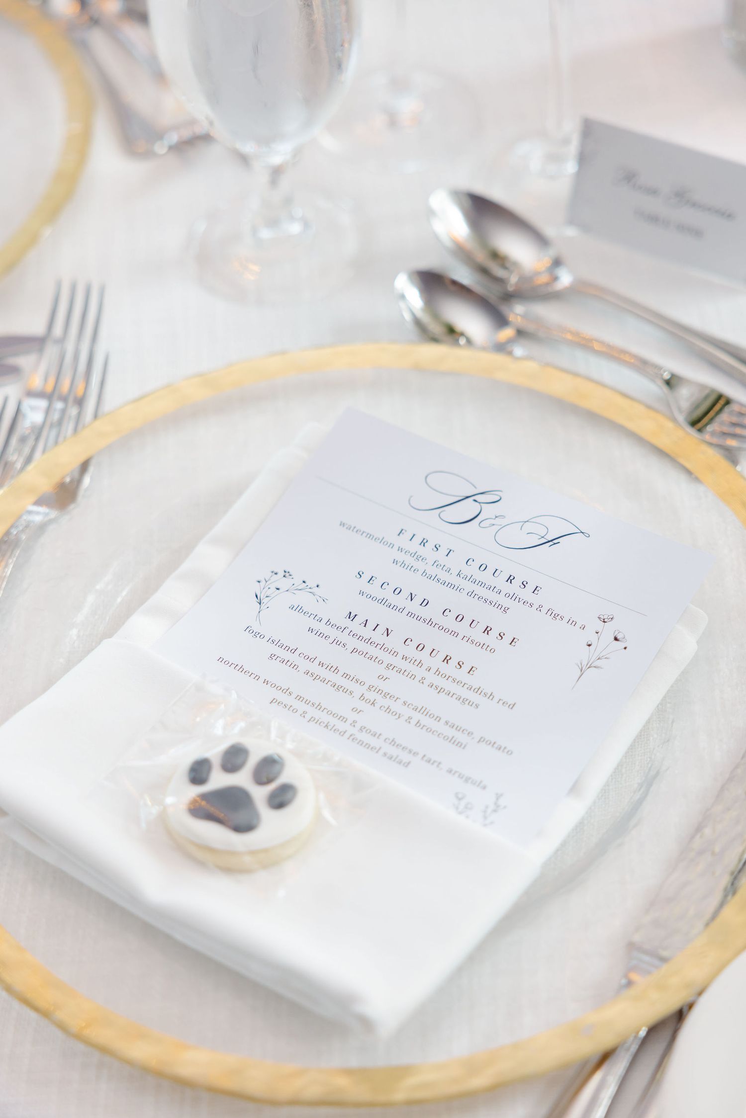 Wedding reception place settings with gold charger plates and elegant monogrammed menus.