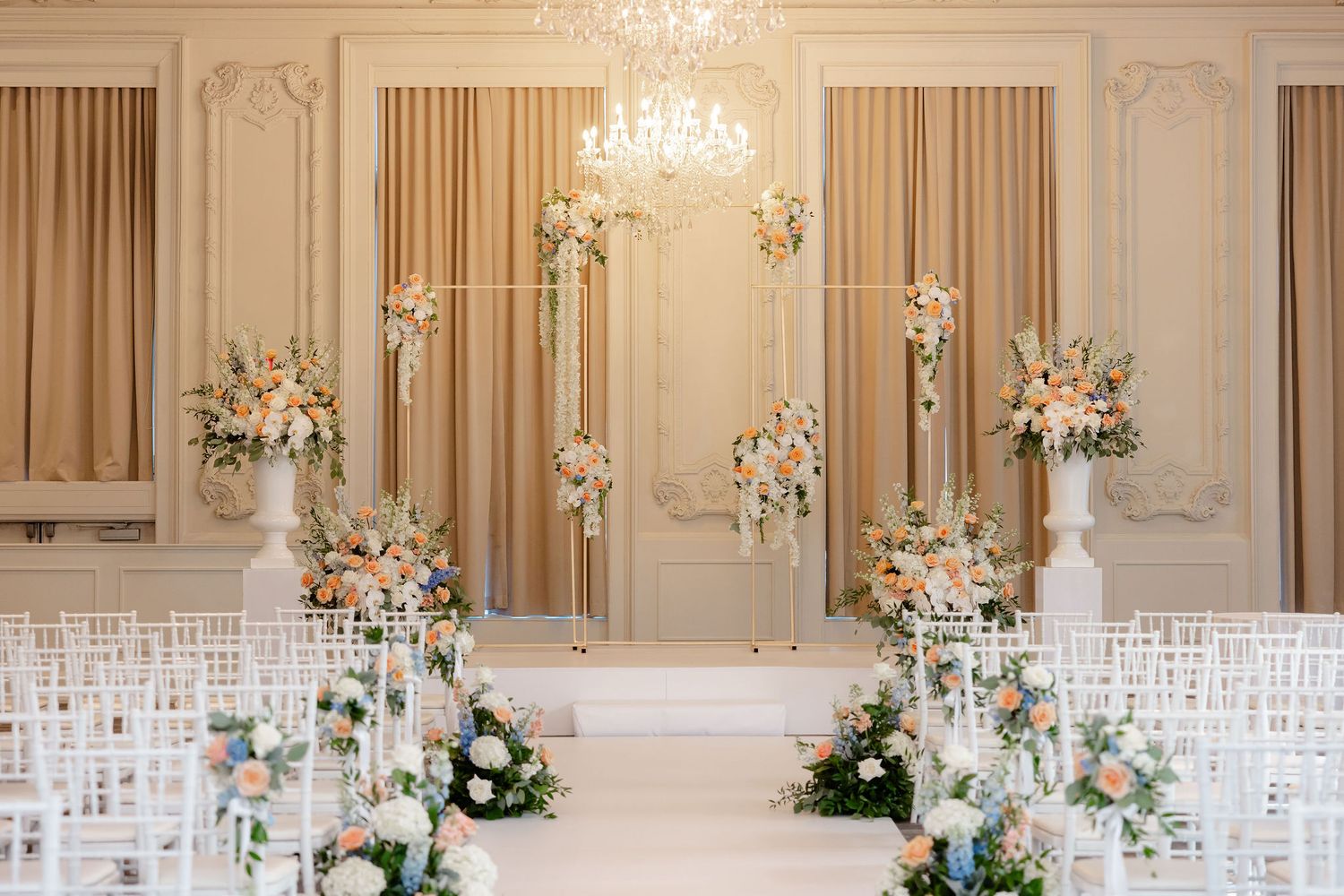 Luxurious wedding reception setup with crystal chandeliers and white floral arrangements.
