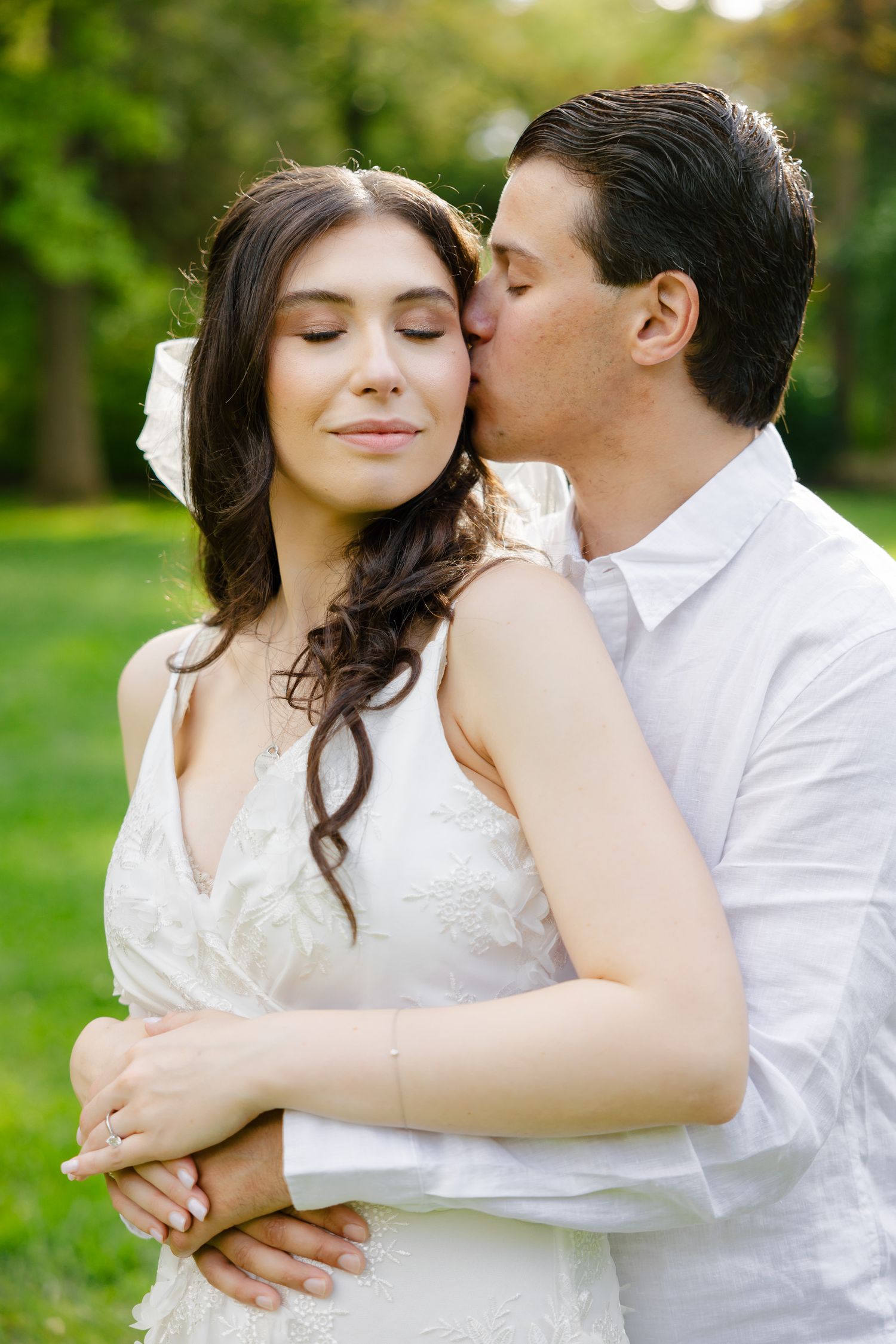 A gentle romantic moment captured in a sunlit garden setting.