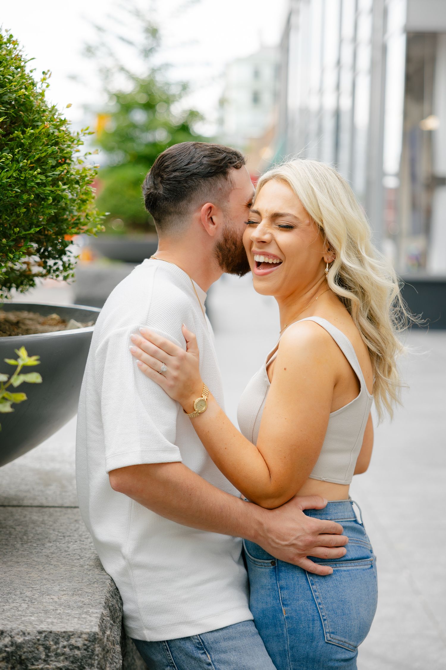 A joyful couple sharing an intimate moment outdoors by urban landscaping.