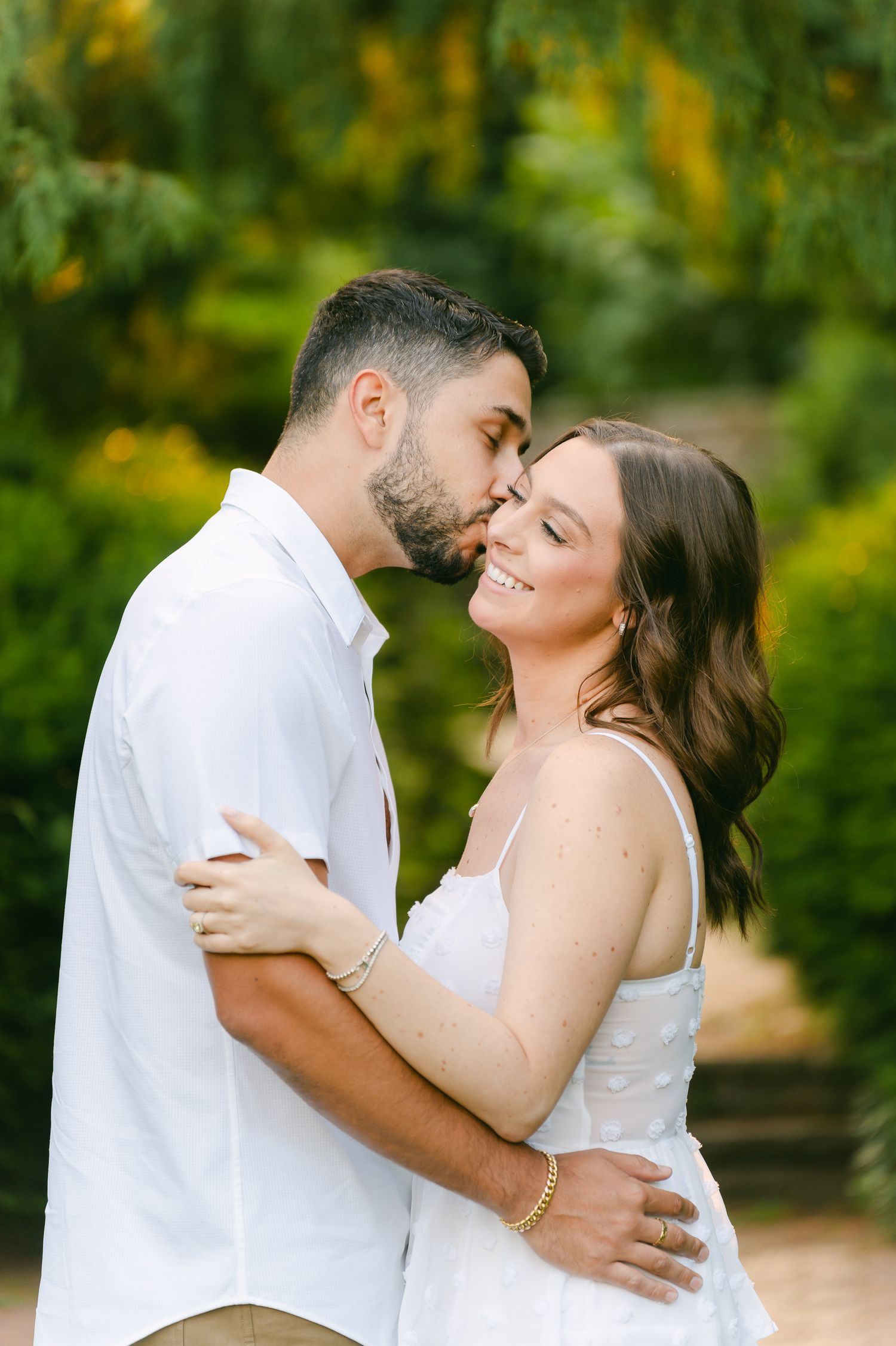 Sweet moment captured between a couple in white and khaki against a vibrant garden backdrop.