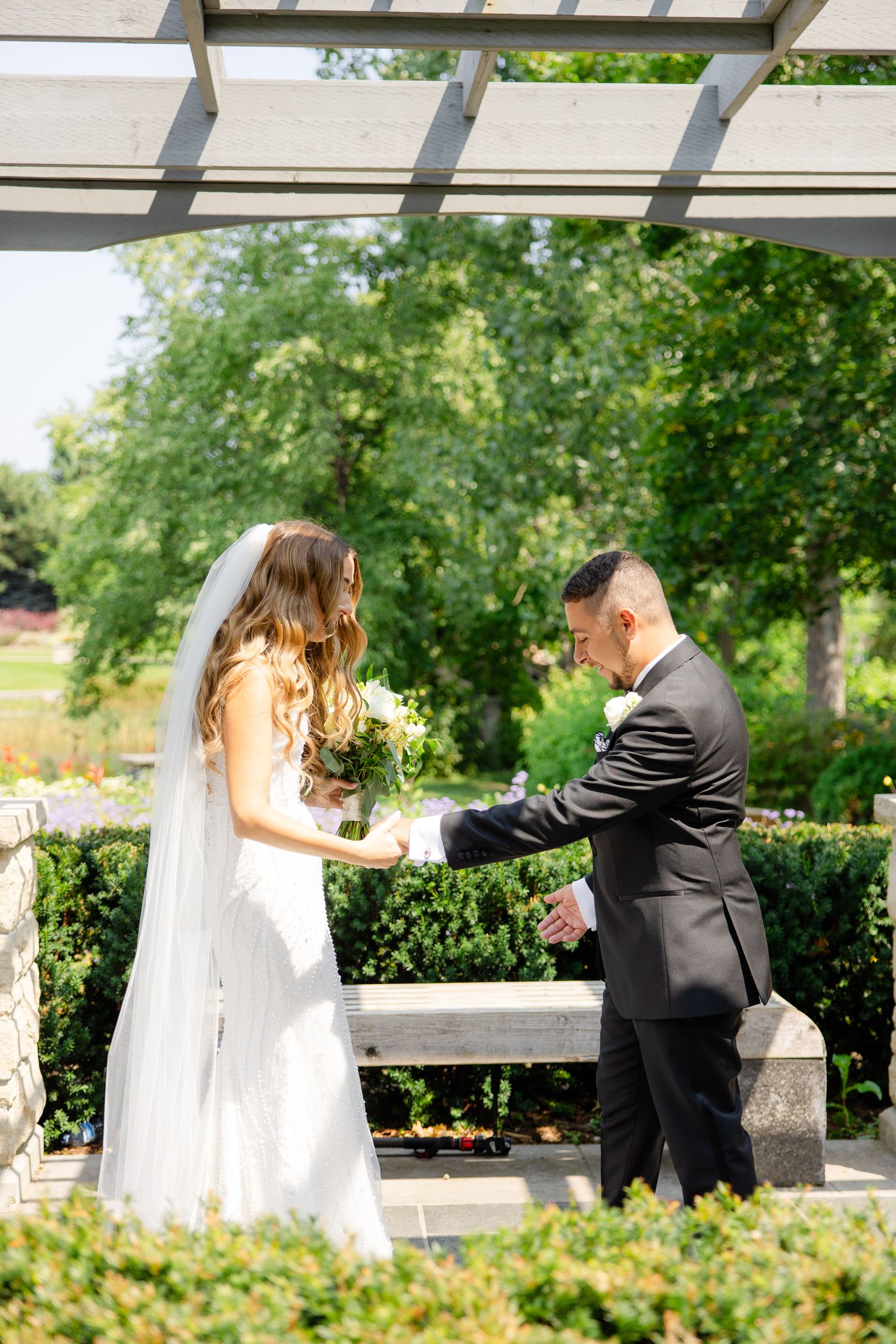 Intimate wedding moment captured as couple exchanges vows under garden pergola.