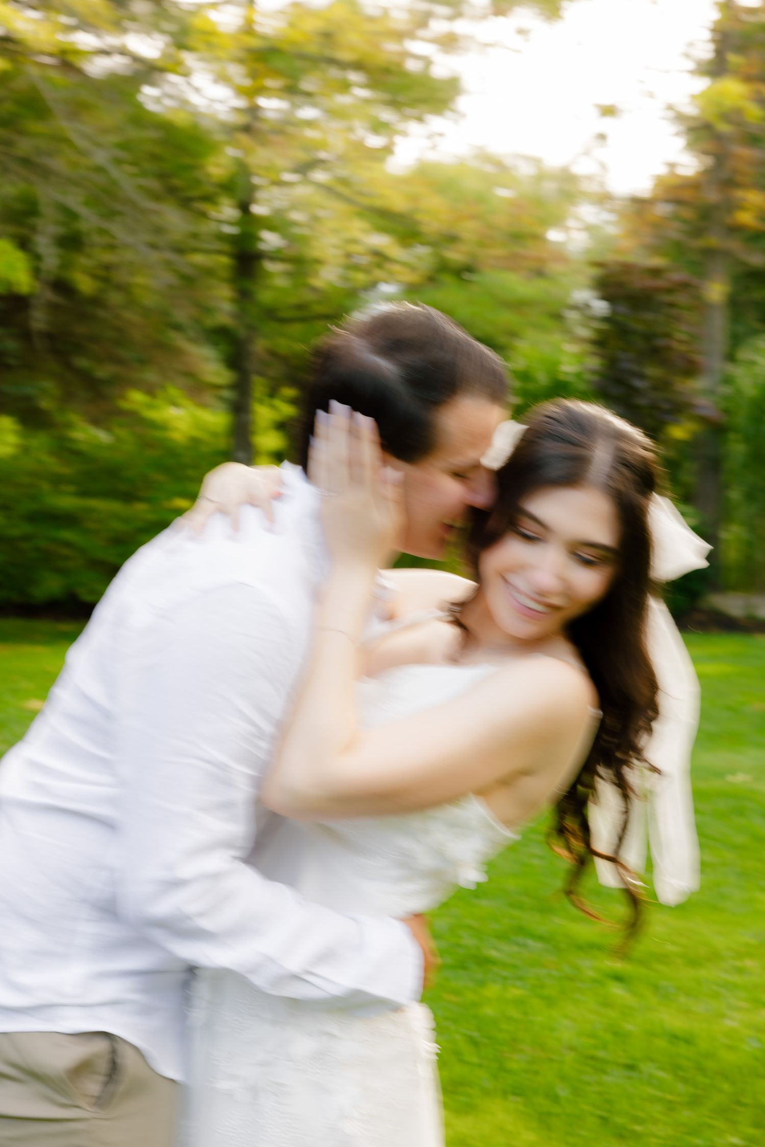 Motion-blurred wedding photo capturing a spontaneous romantic moment in a park.