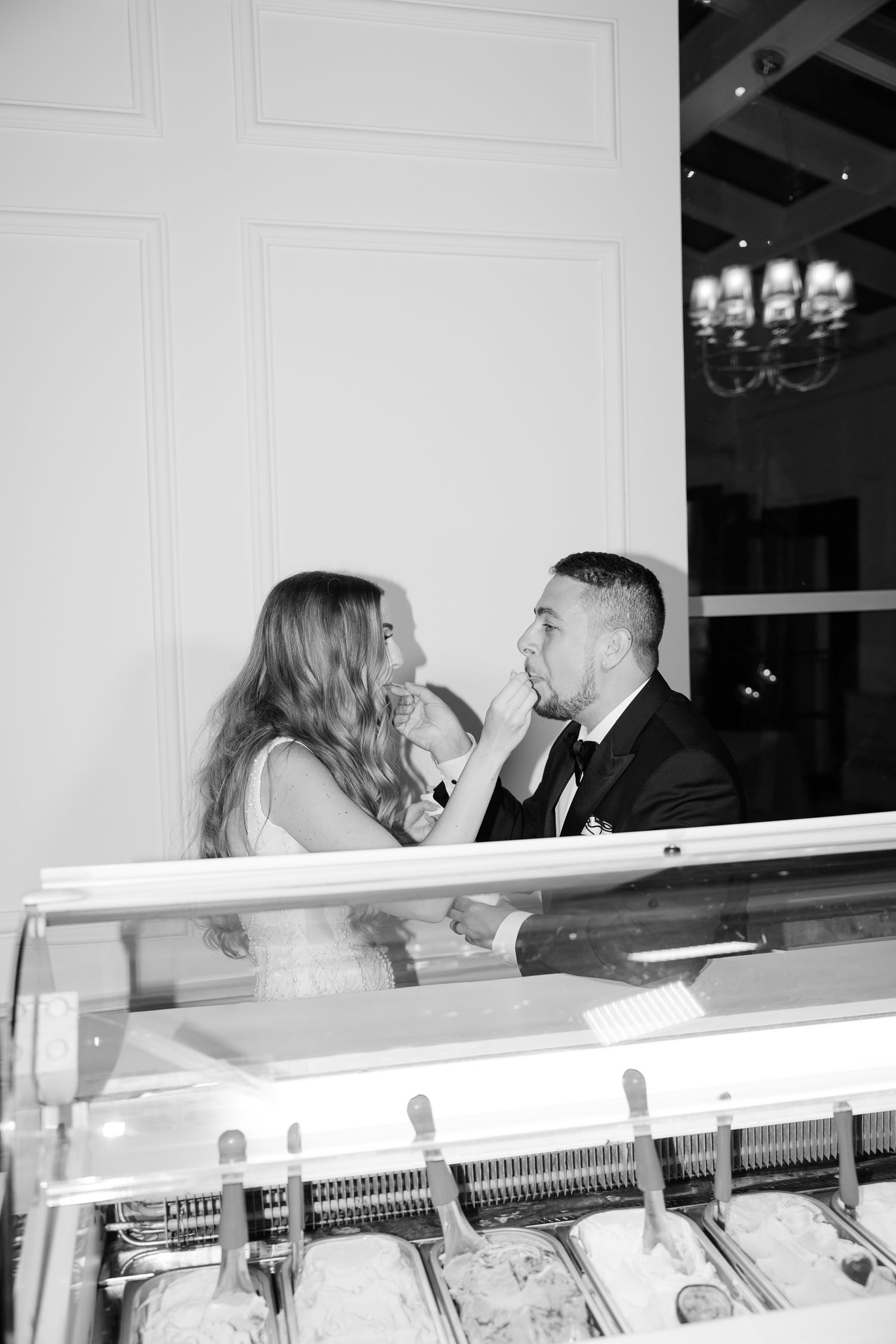 Black and white photo of couple sharing gelato at an elegant dessert station.