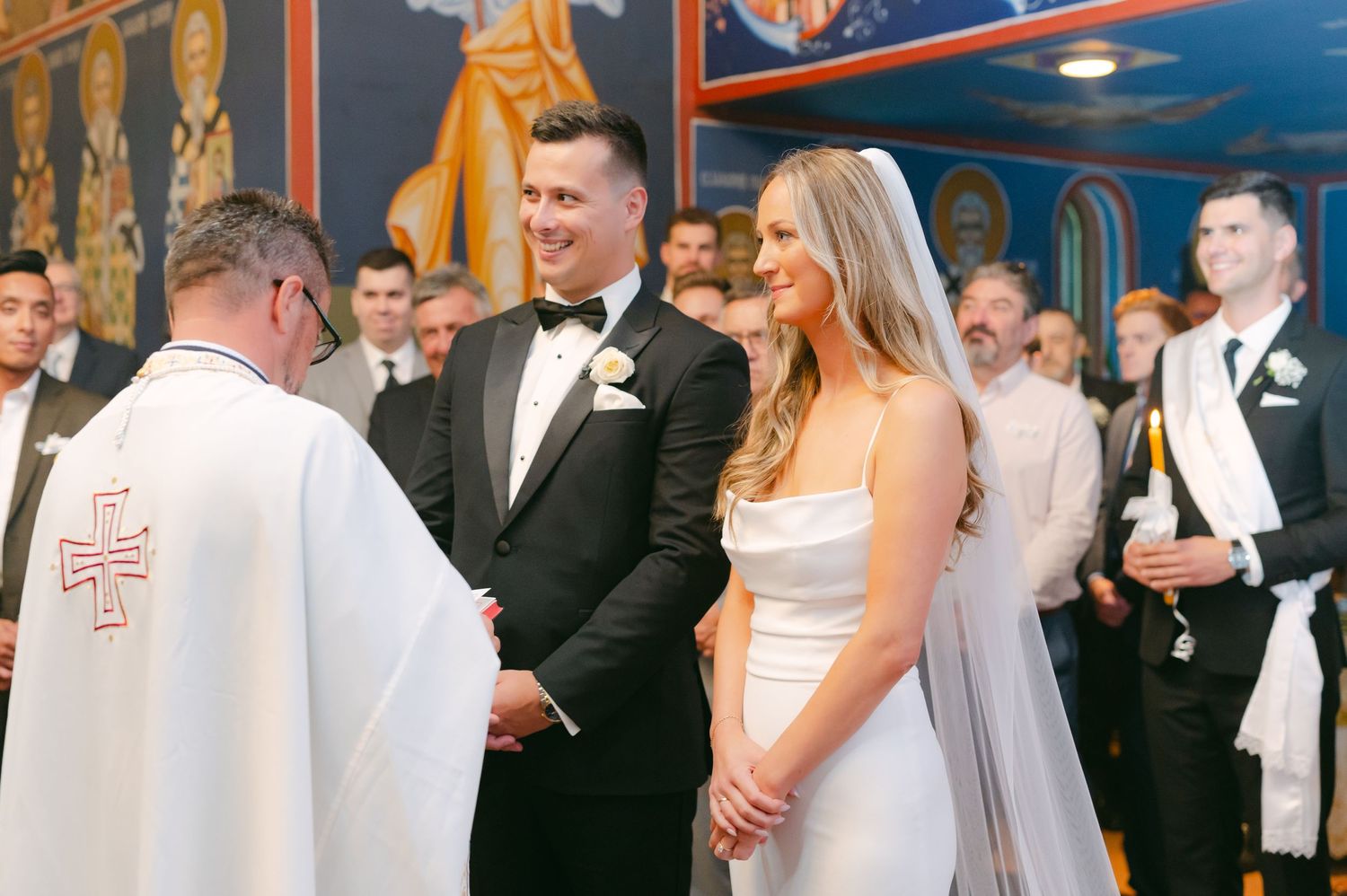 Wedding ceremony with priest in Orthodox church featuring traditional religious icons.