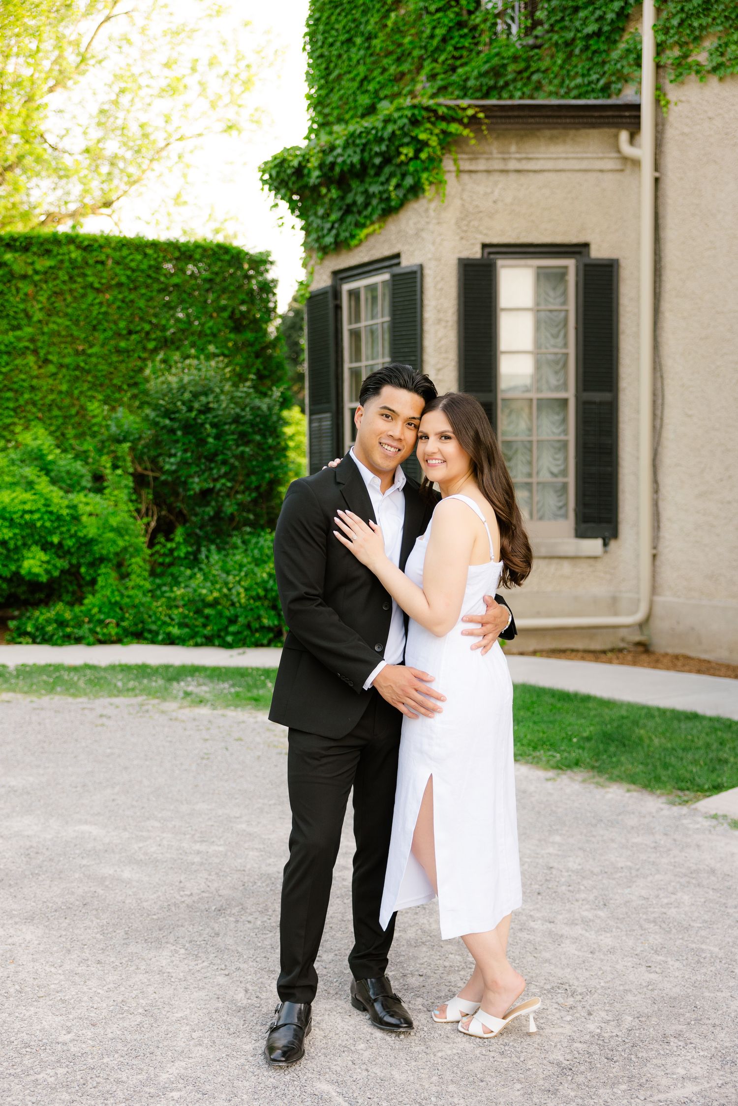 Intimate portrait of couple in formal wear against ivy-covered mansion wall.