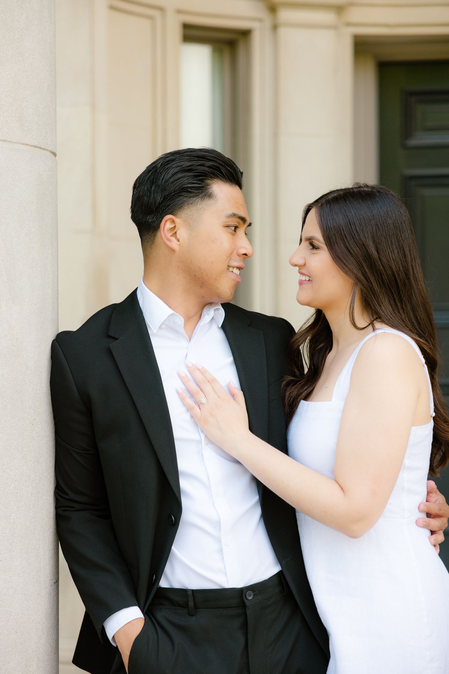 Couple in formal wear gaze at each other lovingly beside classical column and doorway.