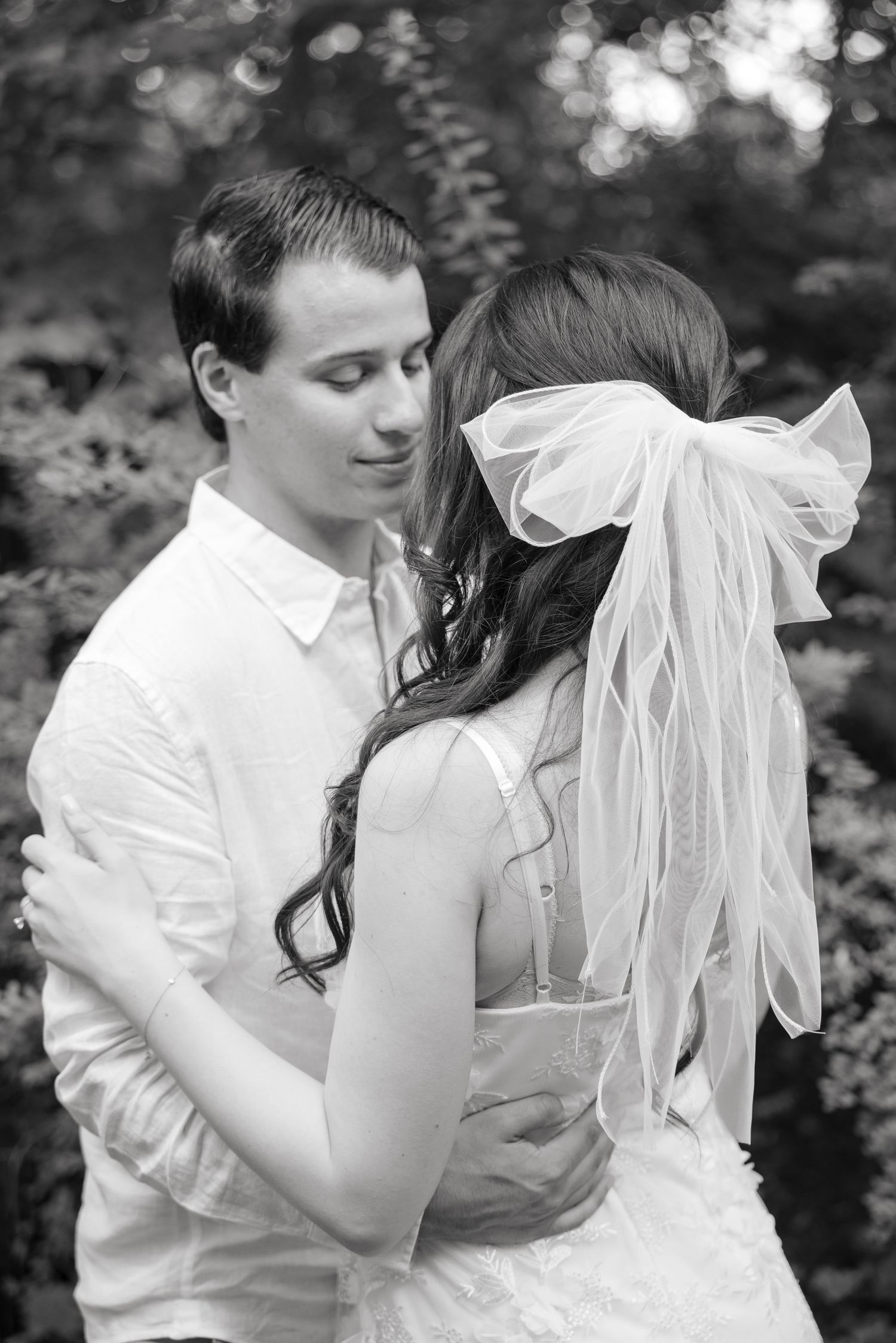 Black and white intimate portrait of a couple embracing in a garden setting.