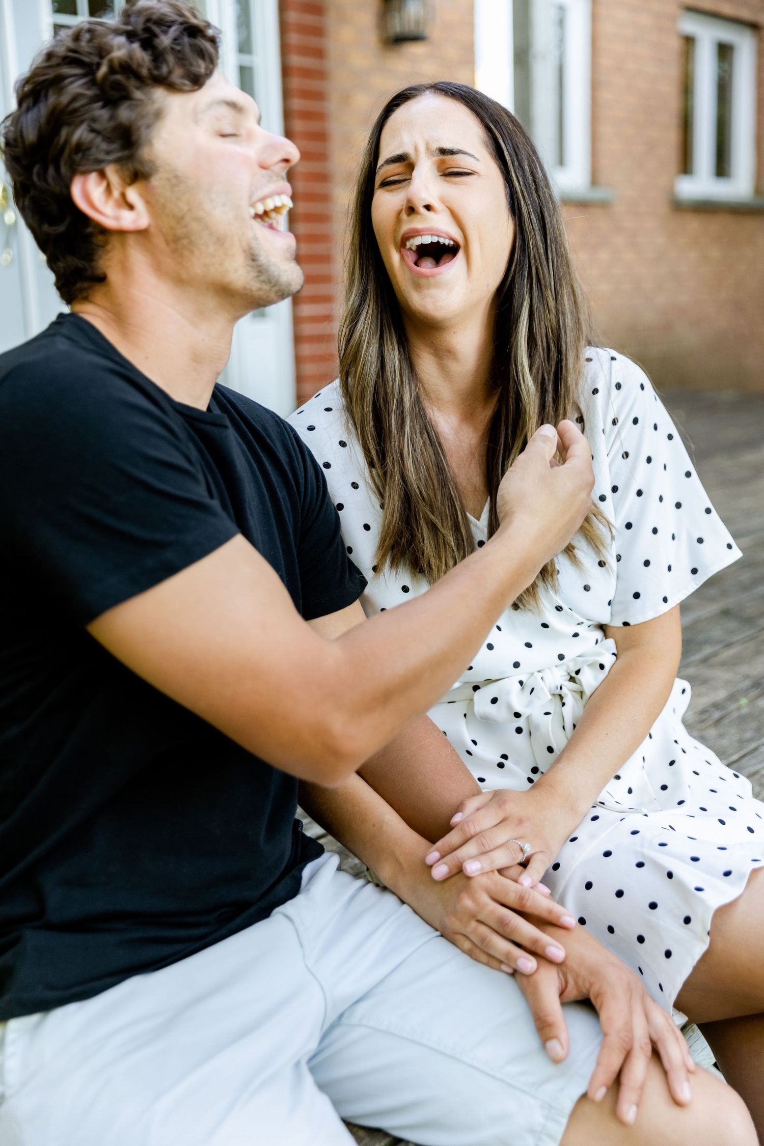 Joyful couple sharing genuine laughter while sitting together outdoors.