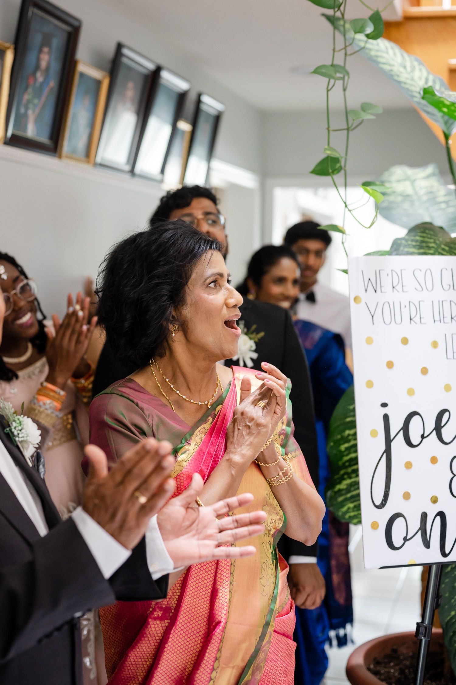 Wedding guests in traditional attire celebrate with excitement during indoor ceremony.
