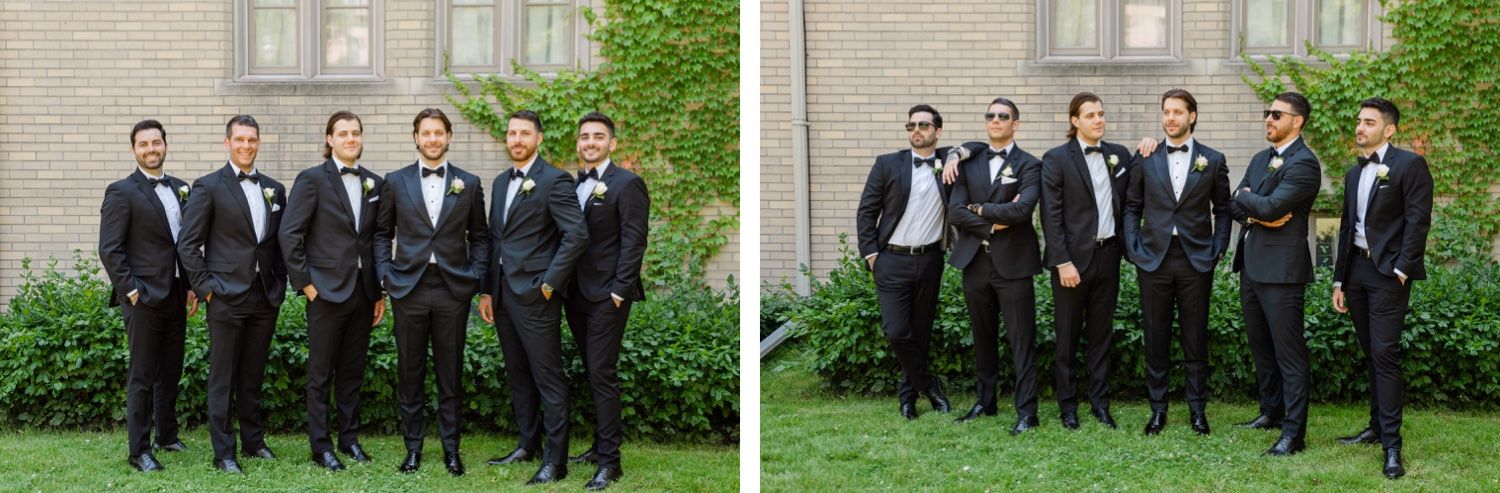 Groomsmen in black tuxedos pose formally outside brick building.