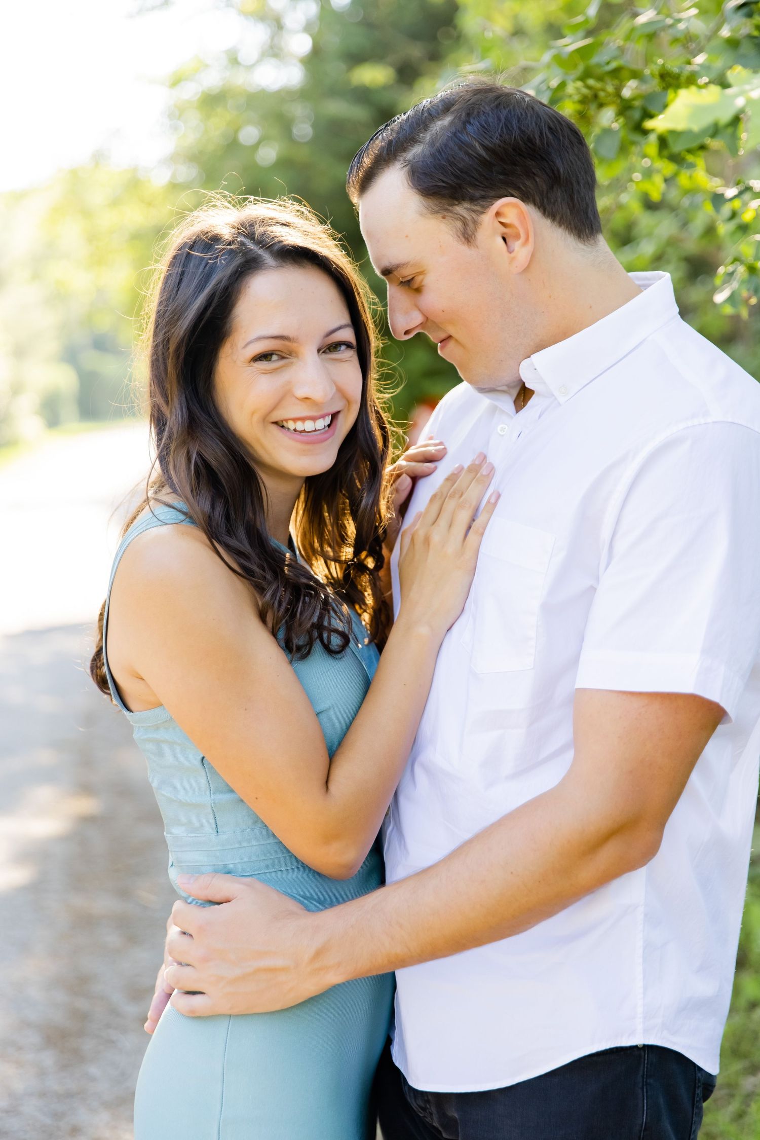 Couple embracing and laughing together on a sunny nature path.