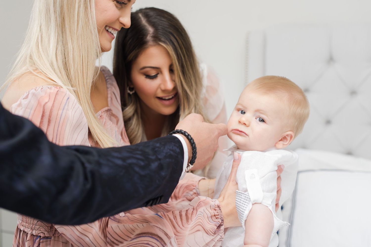Baby being gently held during an intimate gathering in a bright modern room.