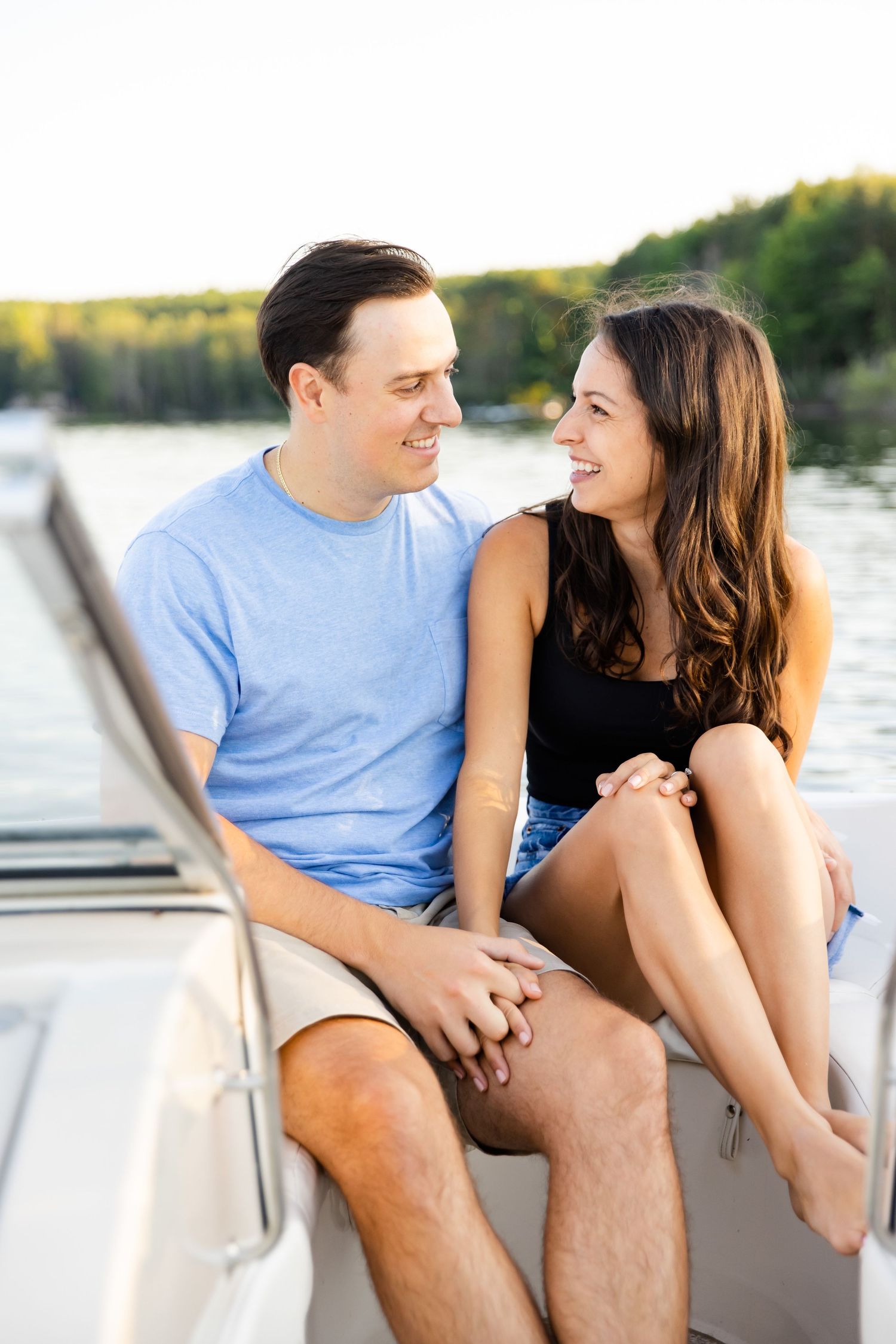 A couple smiles at each other while relaxing on a boat during a sunny afternoon.