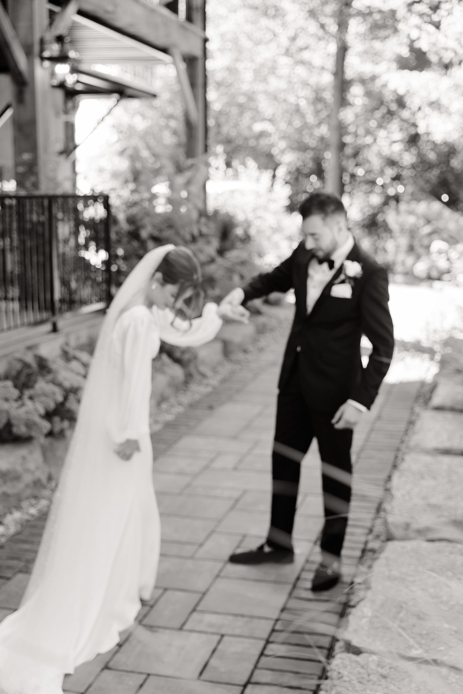 Black and white capture of a joyful wedding moment on a stone garden path.