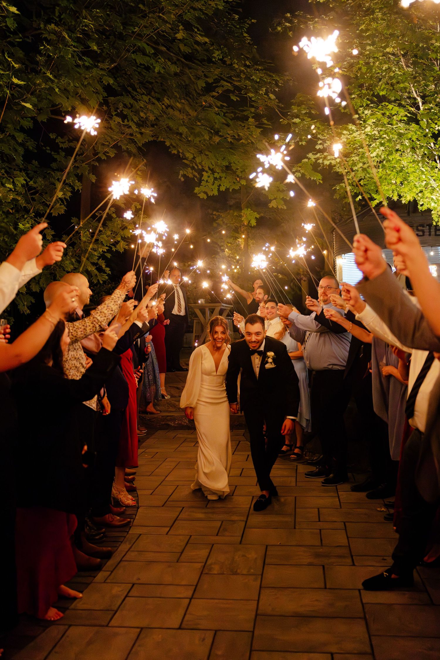 Wedding guests hold sparklers creating a magical light tunnel for the newlyweds.