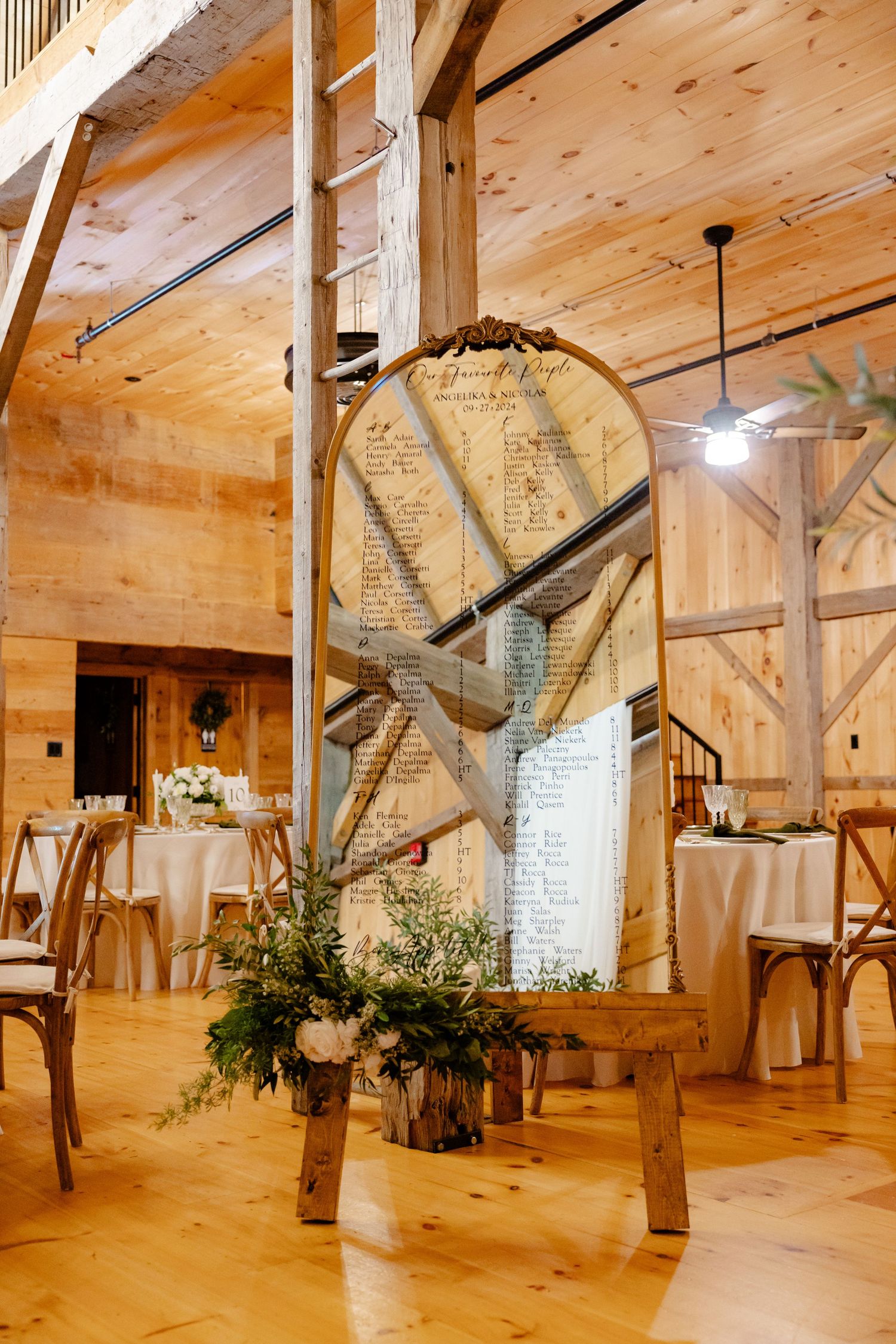 Rustic barn wedding venue interior with seating chart display and wooden crossbeams.
