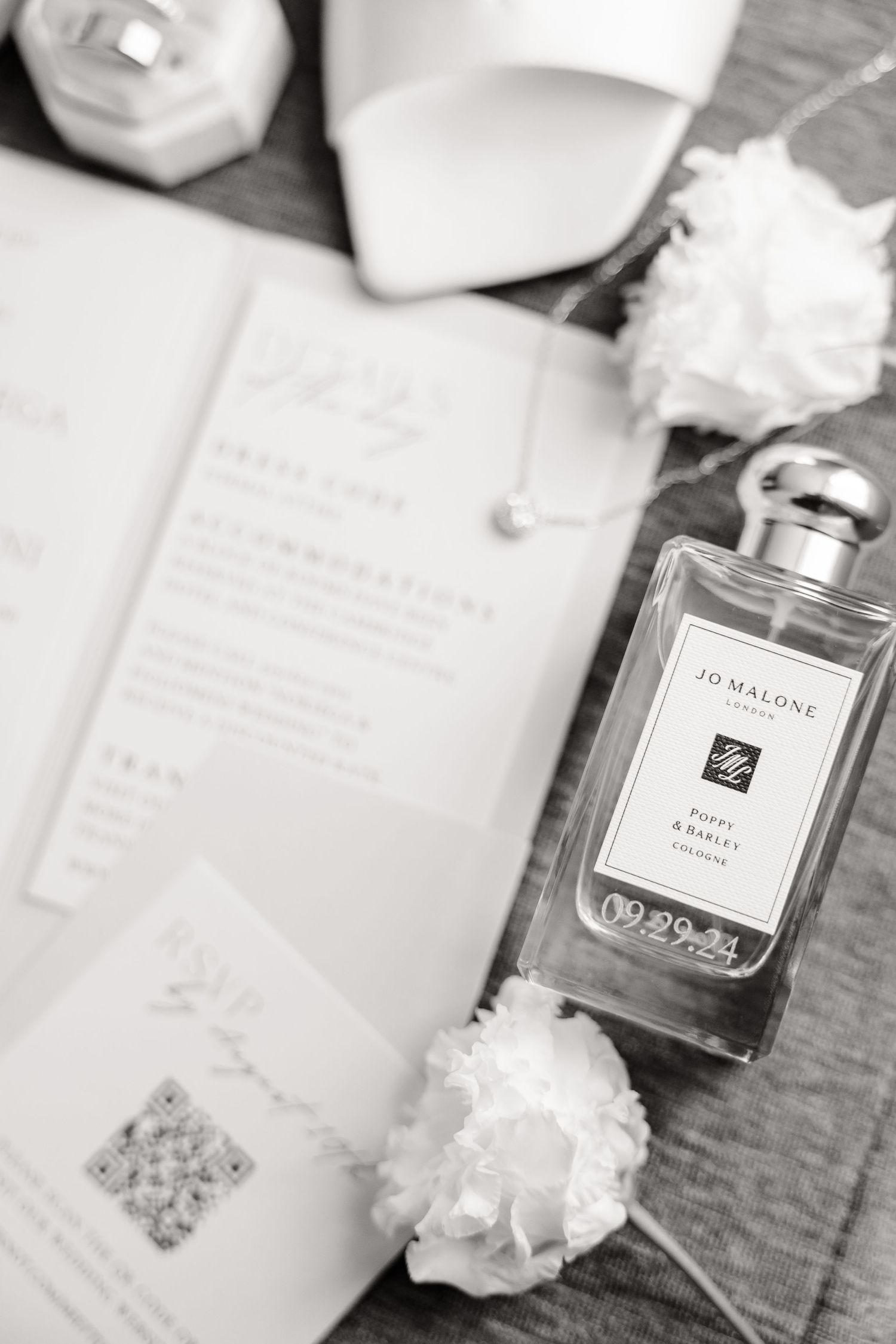 Black and white detail shot of wedding stationery with Jo Malone perfume and white flowers.
