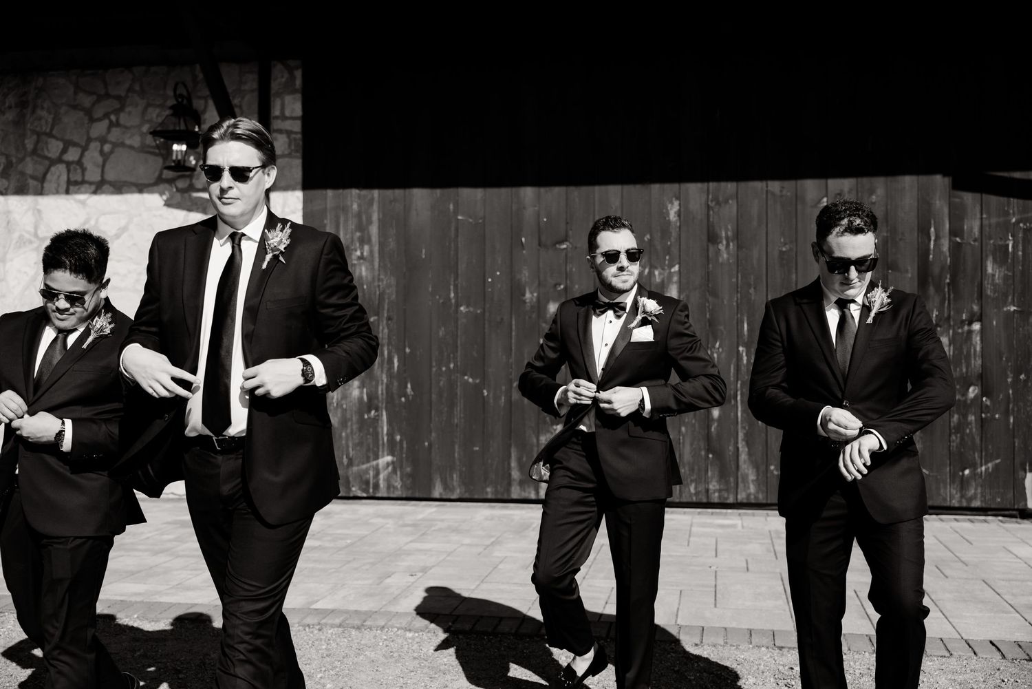 Black and white photo of groomsmen in suits and sunglasses walking with attitude.