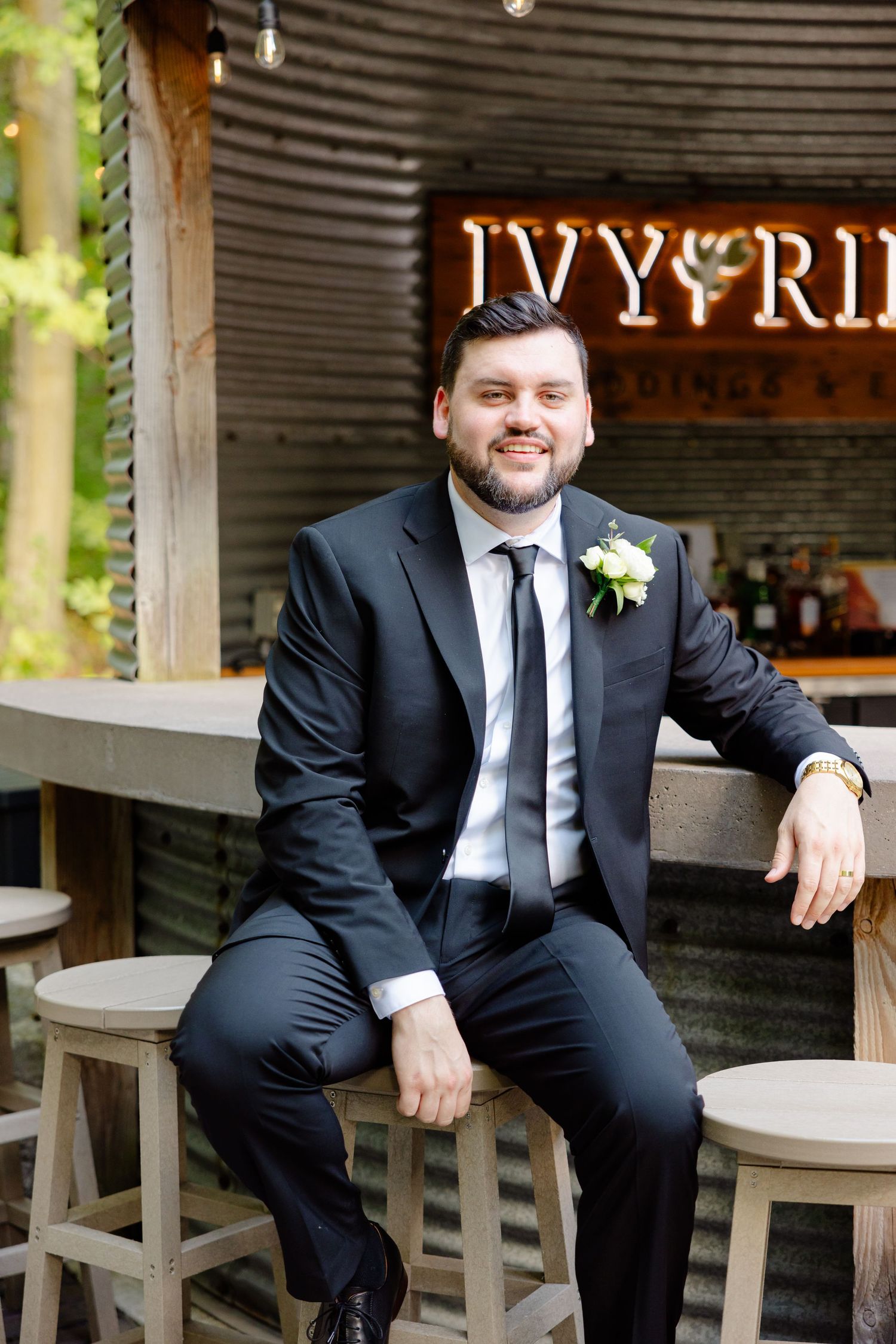Wedding day portrait at rustic outdoor bar venue with neon signage.