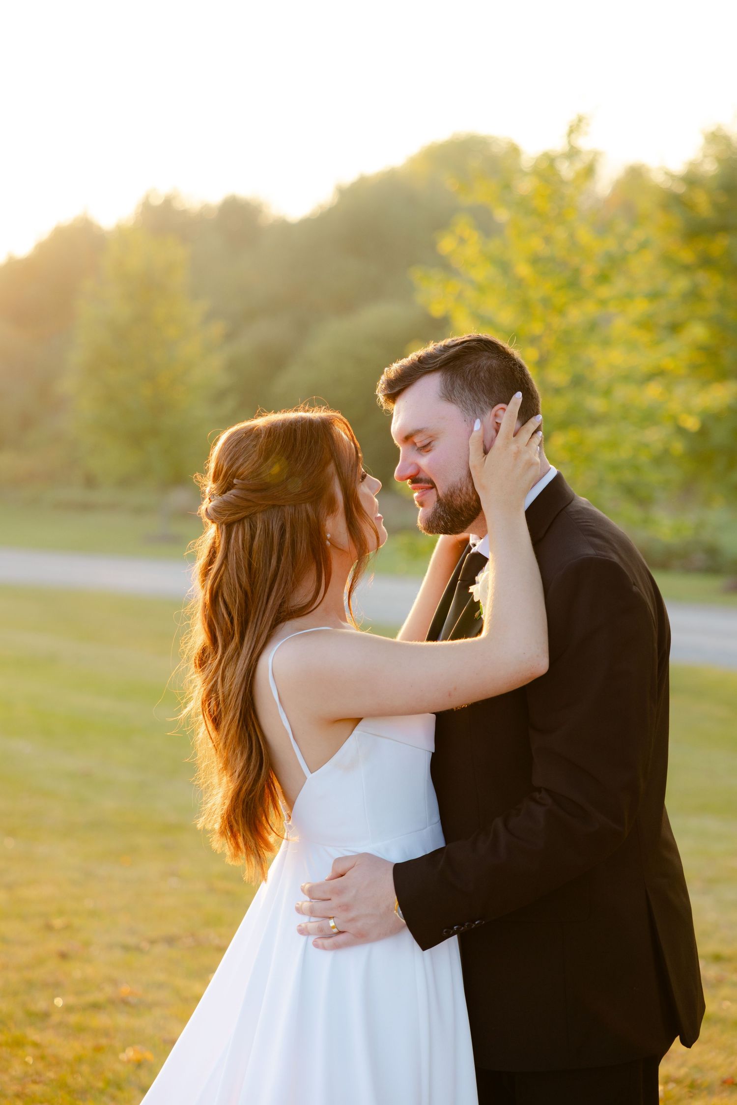 Sunset wedding photograph captures romantic moment between couple in outdoor setting with golden light.