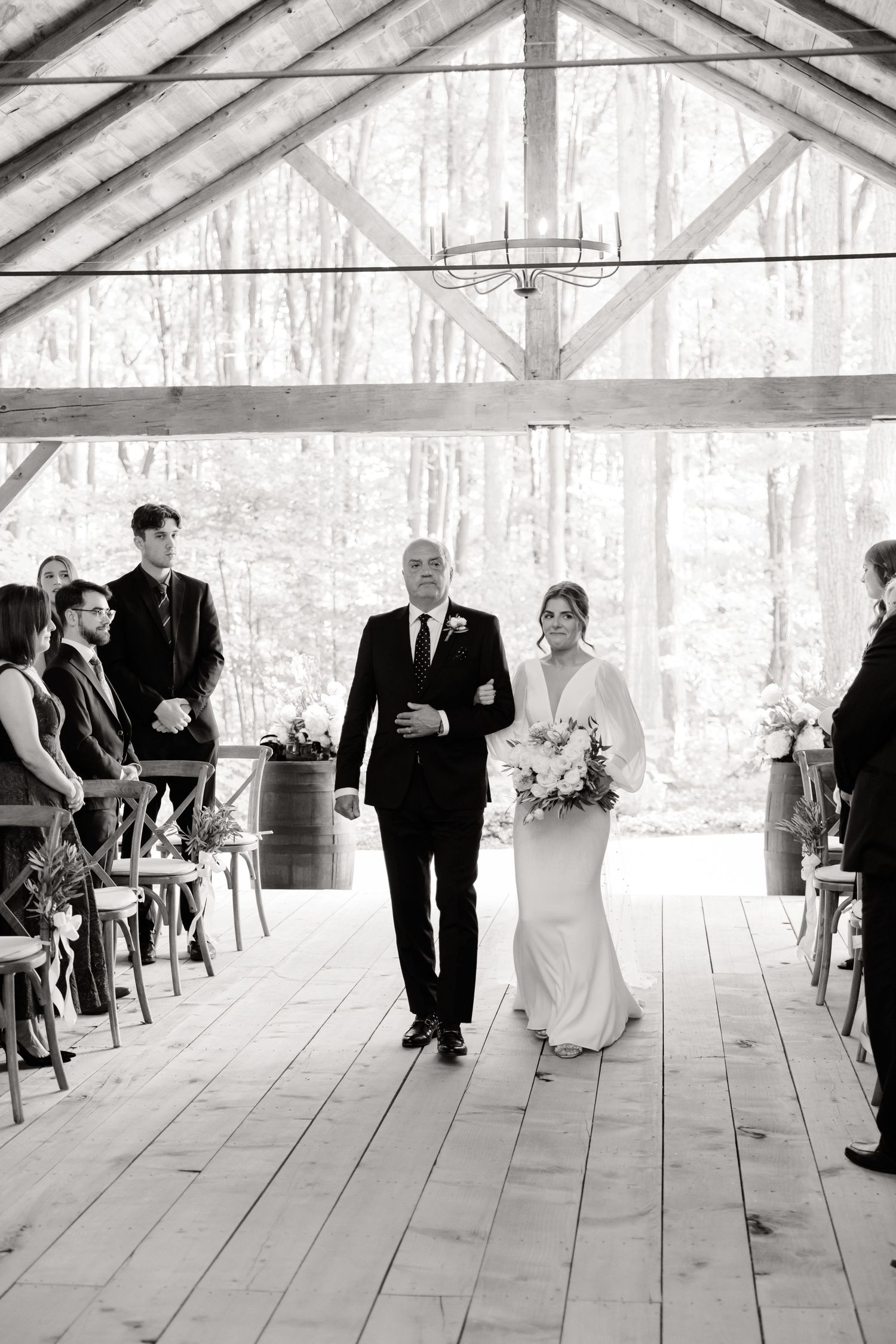 A wedding ceremony in a rustic wooden barn venue with exposed beams and natural light.
