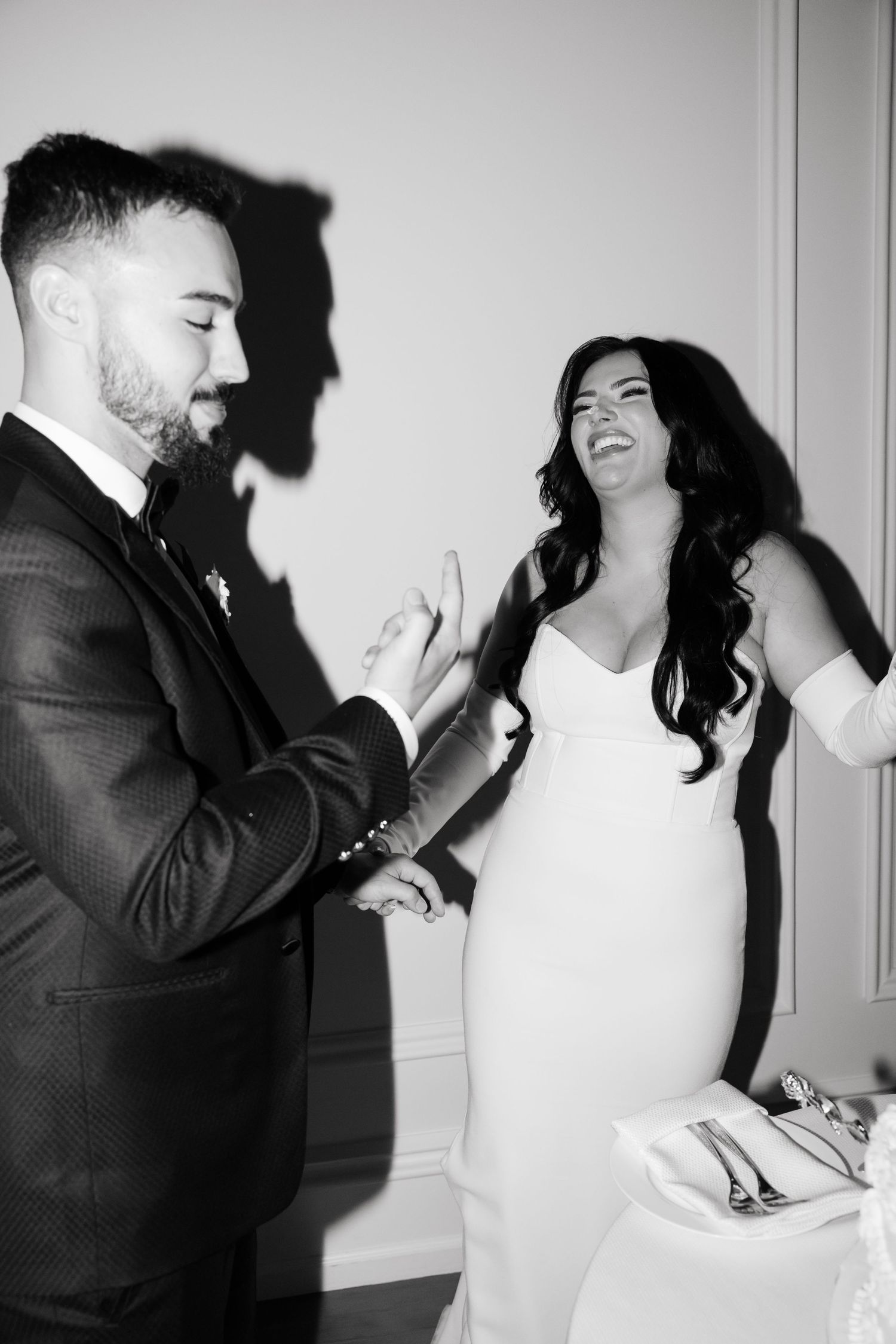 Black and white photo of couple sharing laughter during their wedding cake moment.