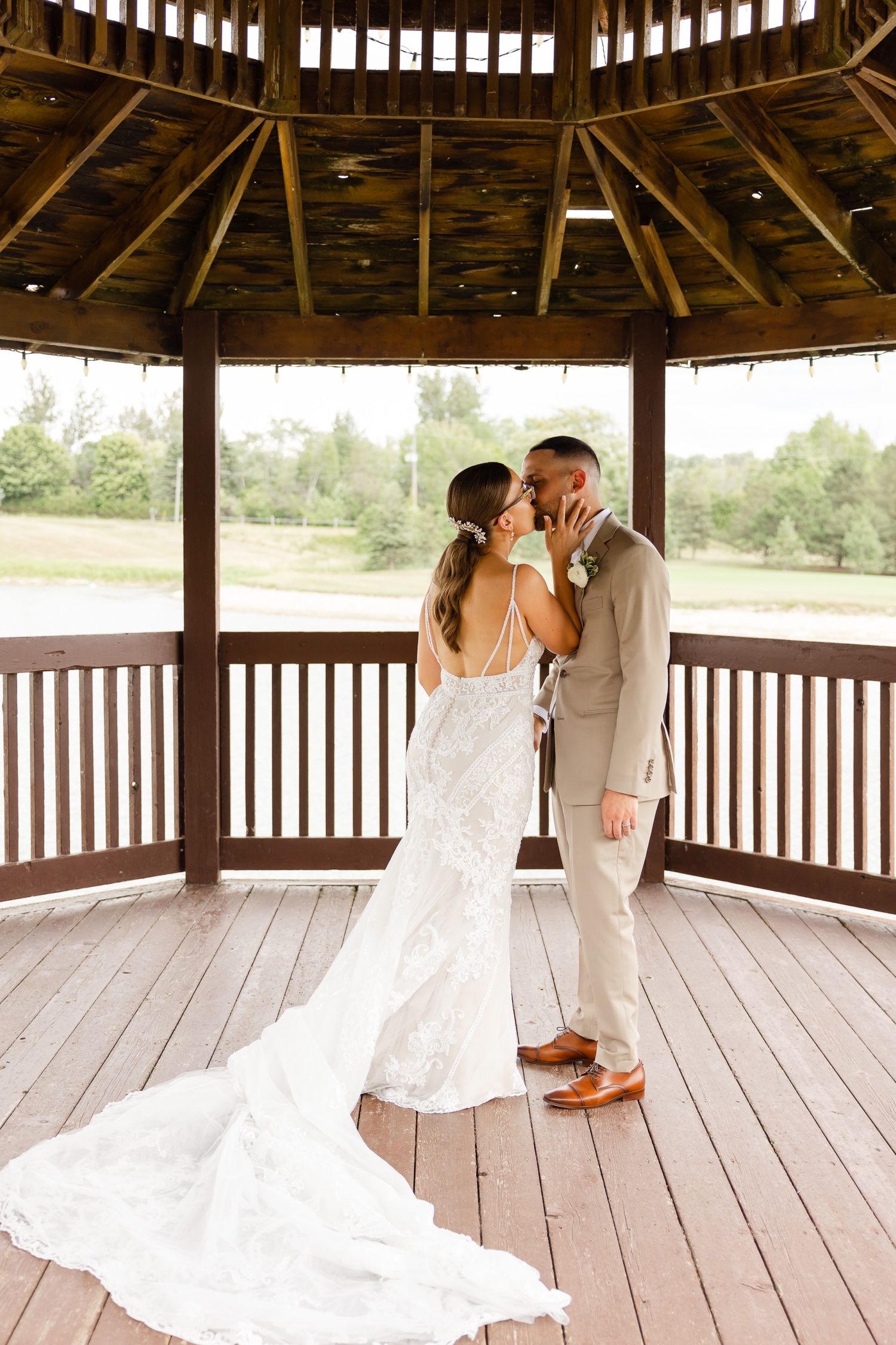 A romantic moment captured between newlyweds in a wooden gazebo with a flowing white train.
