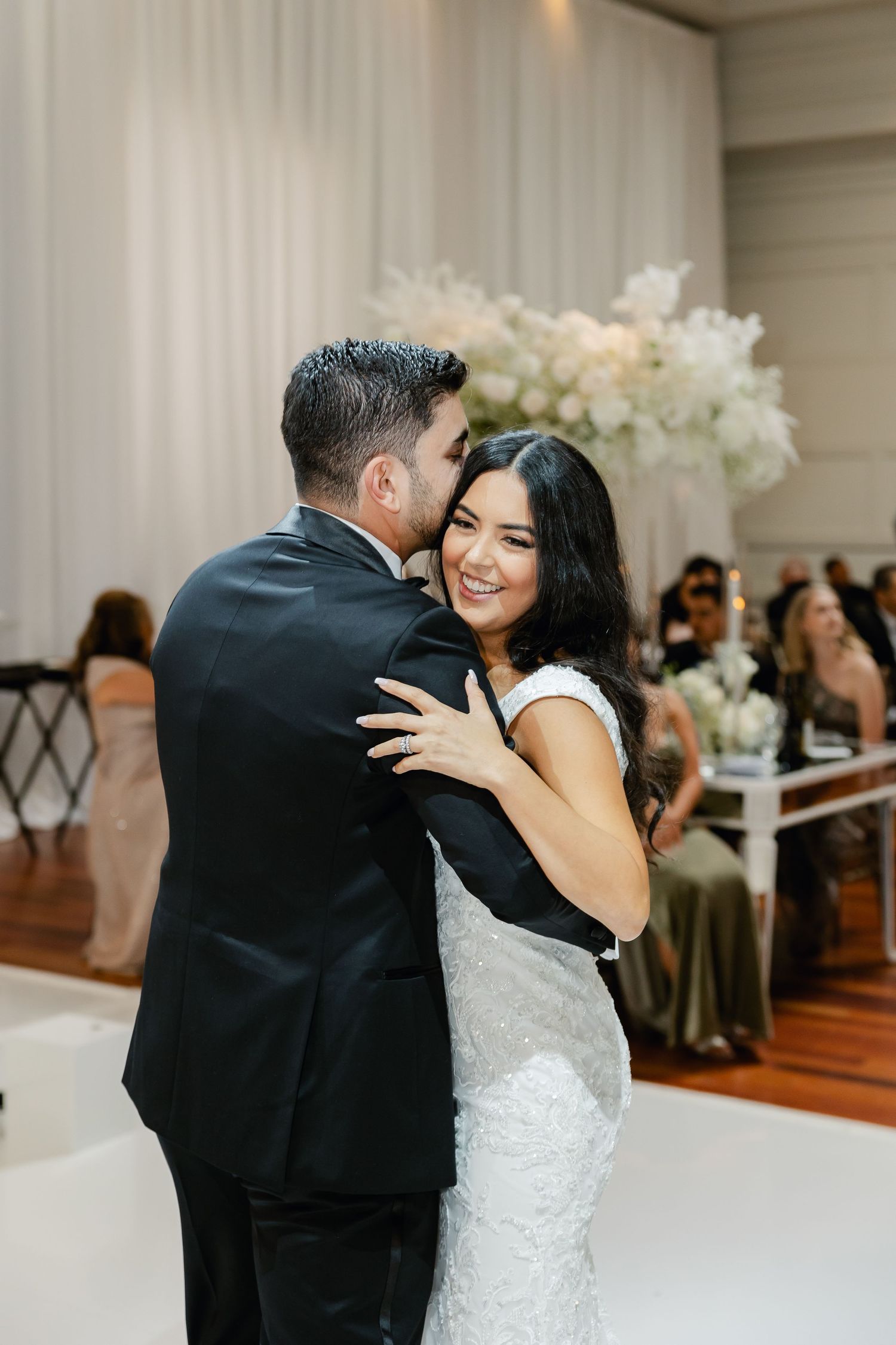 A romantic first dance moment at an elegant wedding reception with white floral decorations.
