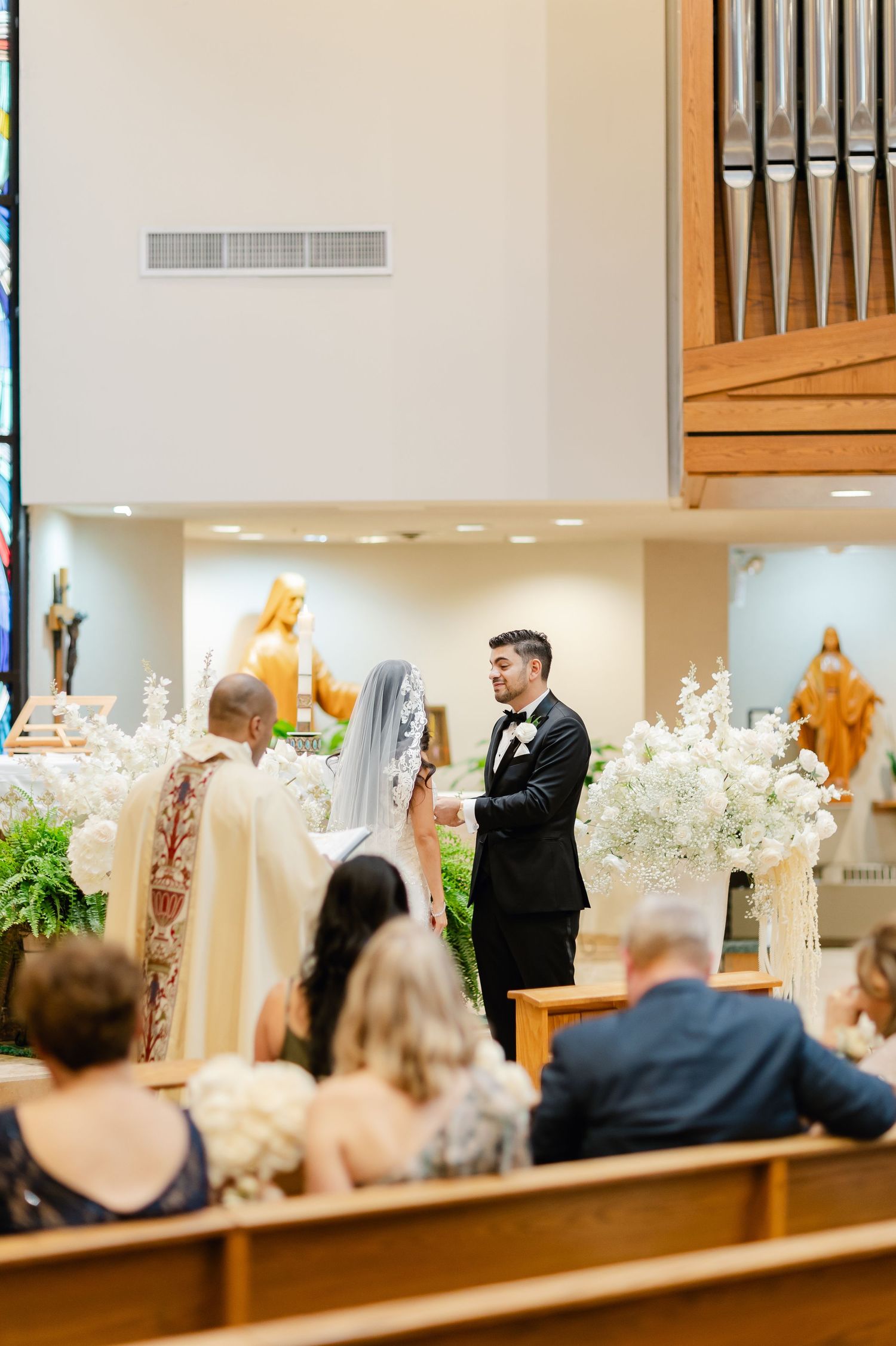 Wedding ceremony taking place in a church with an organ and religious statues in the background.
