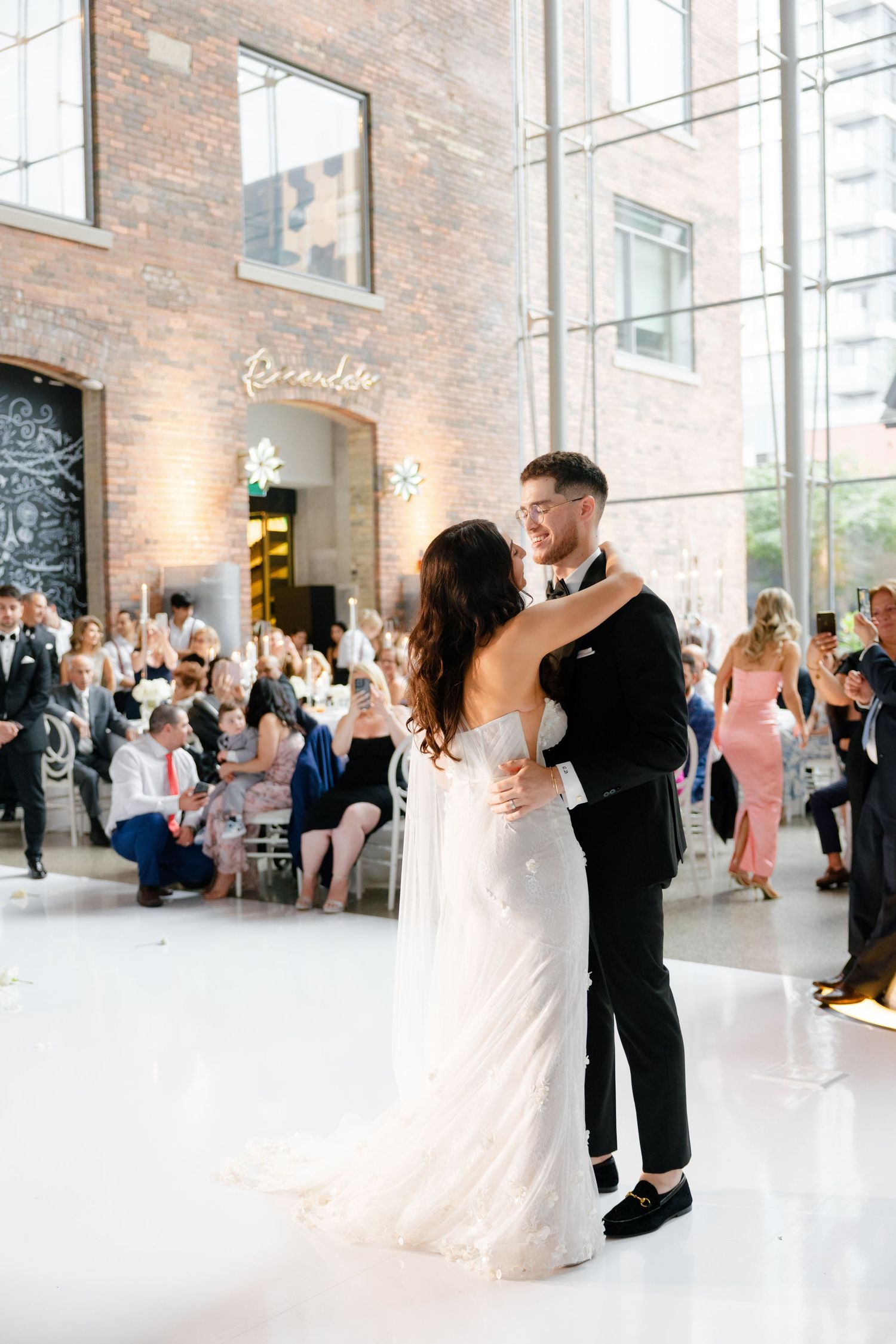 Wedding celebration in a rustic brick venue with black chalkboard wall and white floors.