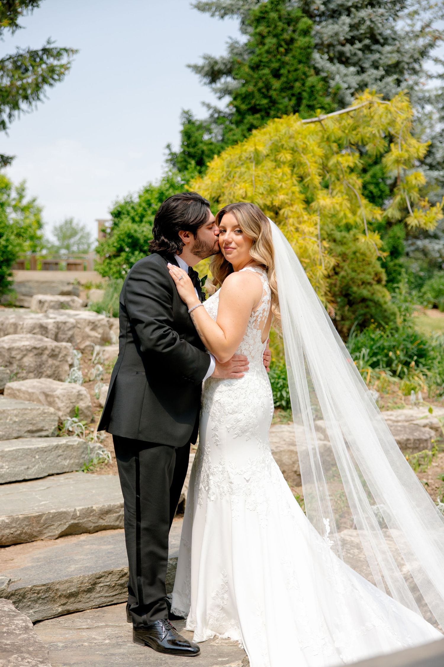 Romantic wedding portrait on stone steps with bright yellow foliage and flowing cathedral veil.