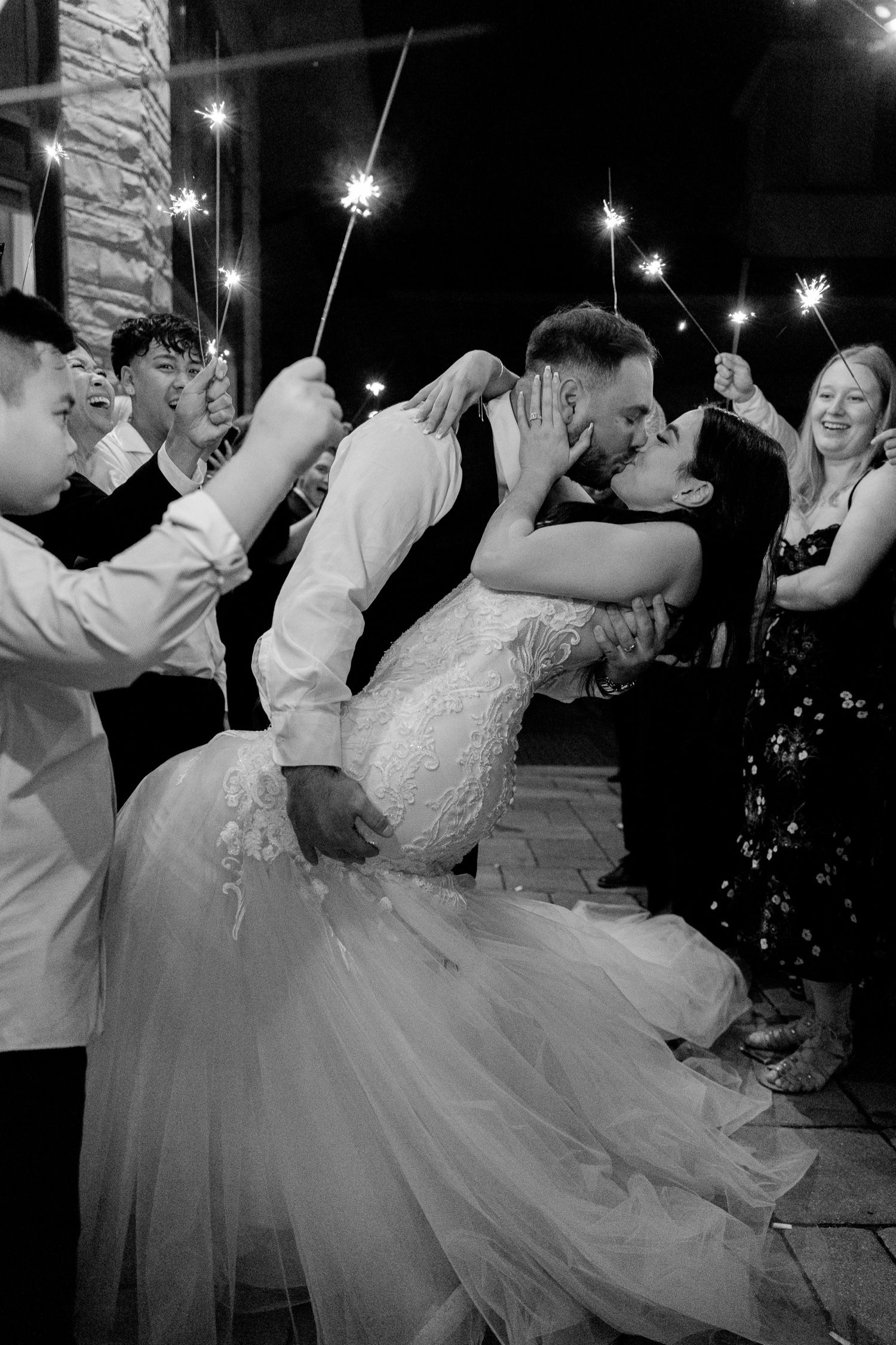 Romantic sparkler exit moment captured in black and white during evening wedding celebration.