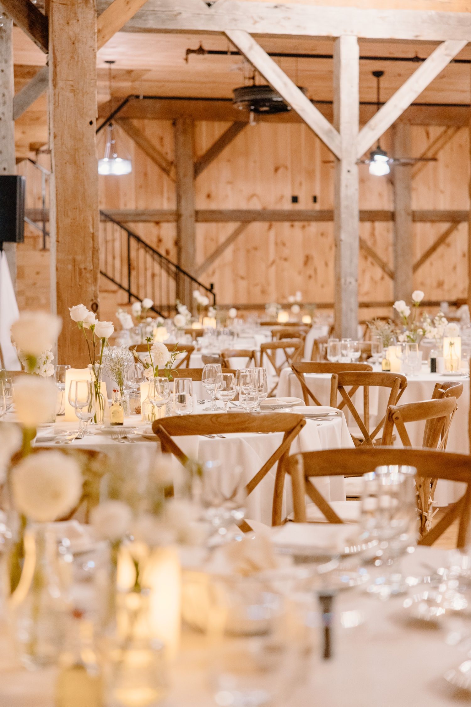 Rustic barn wedding venue interior with wooden beams and elegant table settings.