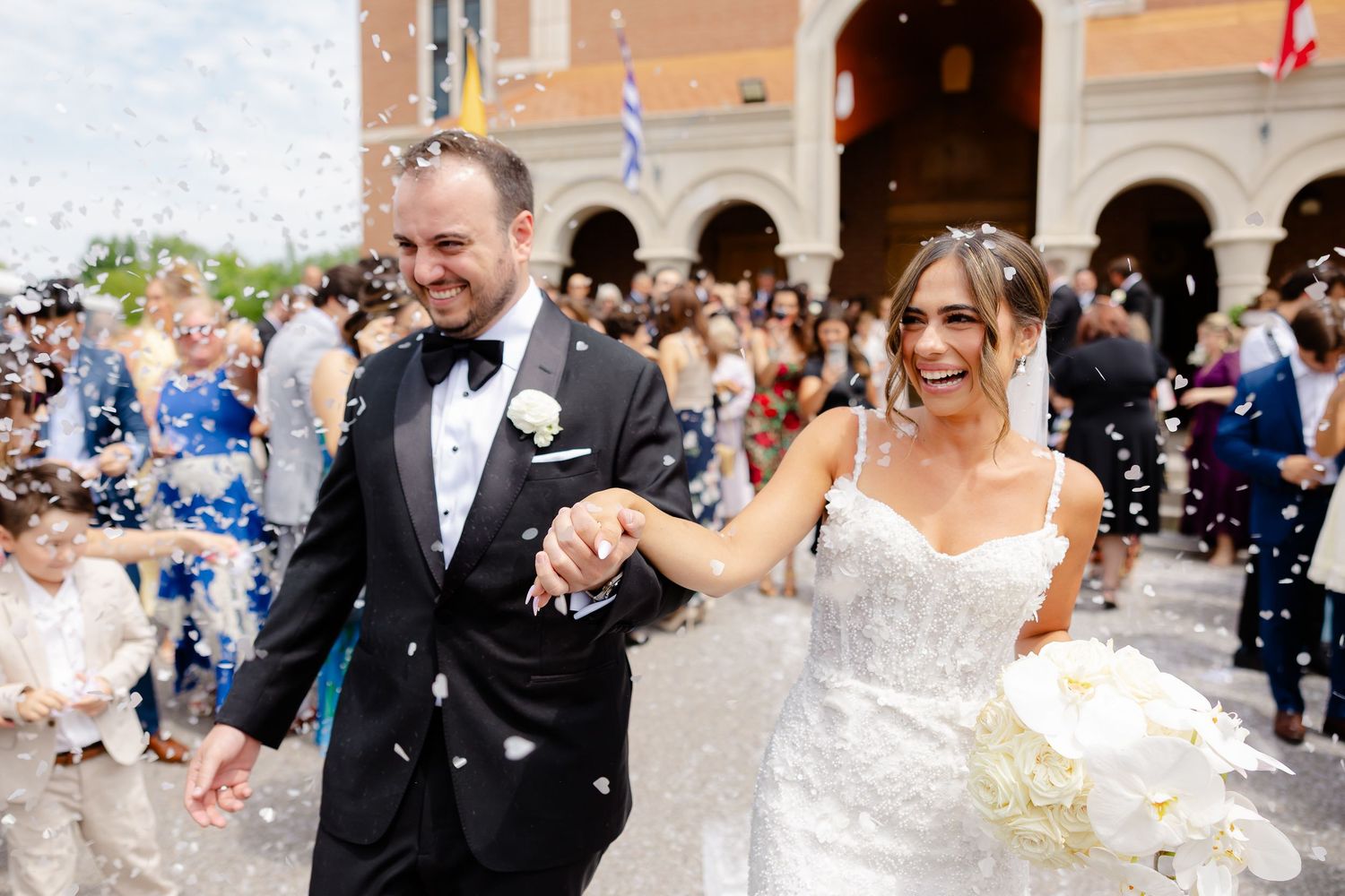 Guests shower the newlyweds with white confetti during their joyful outdoor wedding celebration.