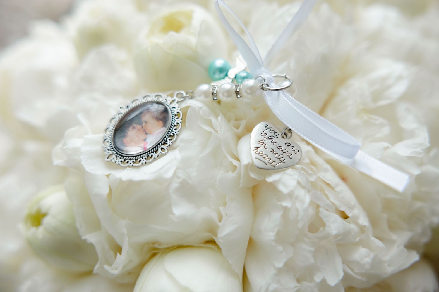 Vintage-style pendant with crystals and ribbon nestled in white flowers.