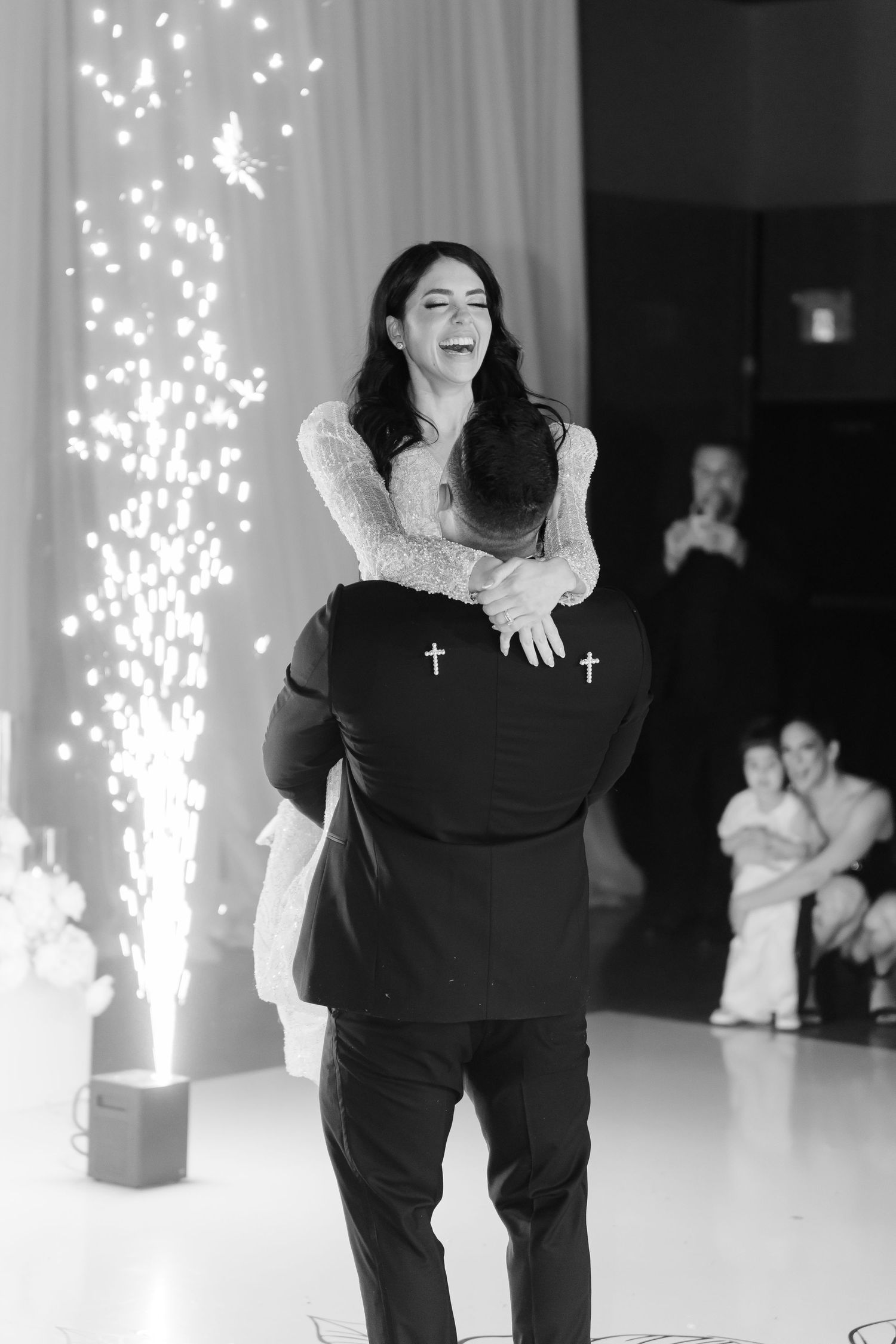 Joyful dance moment captured in black and white with sparkling lights in background.