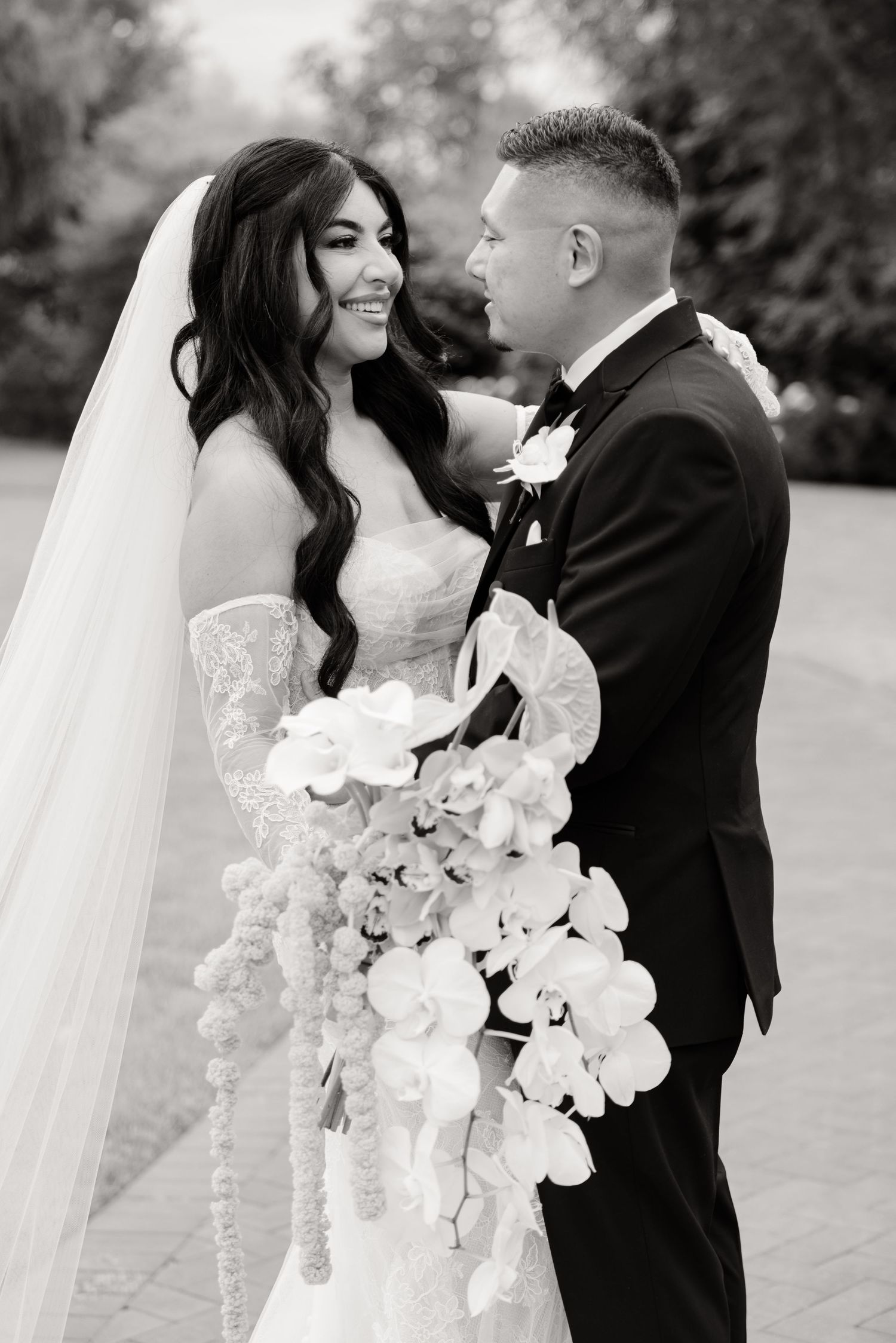 A series of romantic black and white wedding photos showing a couple with white orchid bouquets and formal attire.