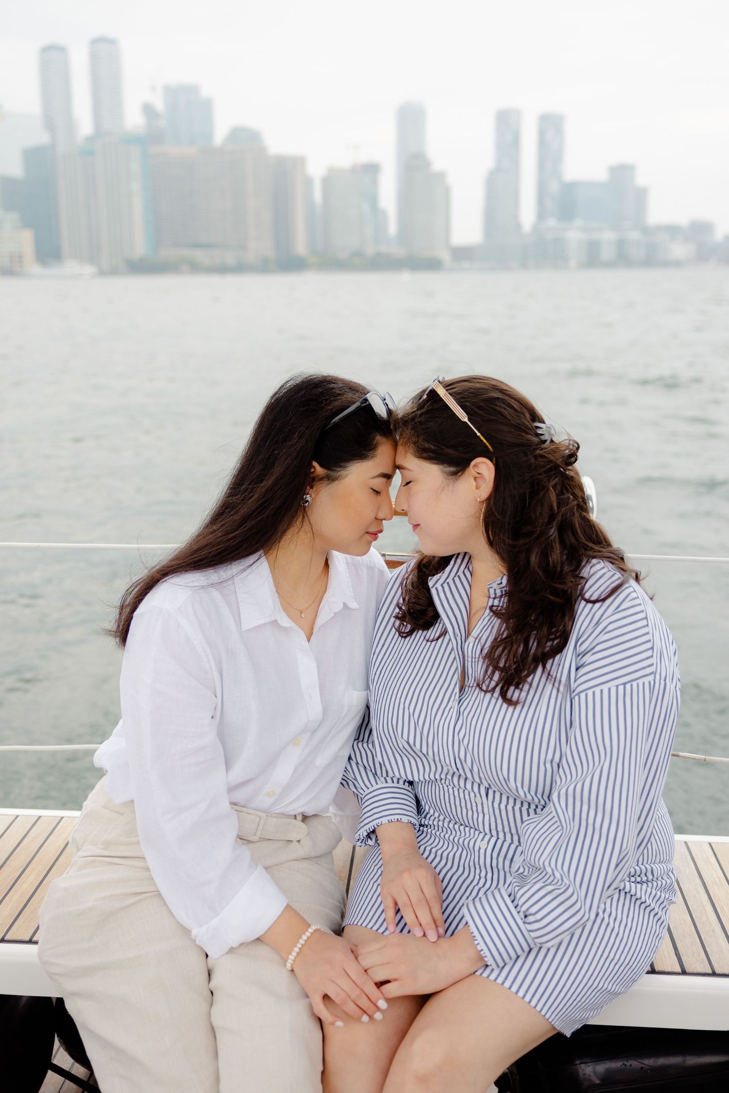 Two people share an intimate moment on a pier with the New York City skyline visible in the misty background.