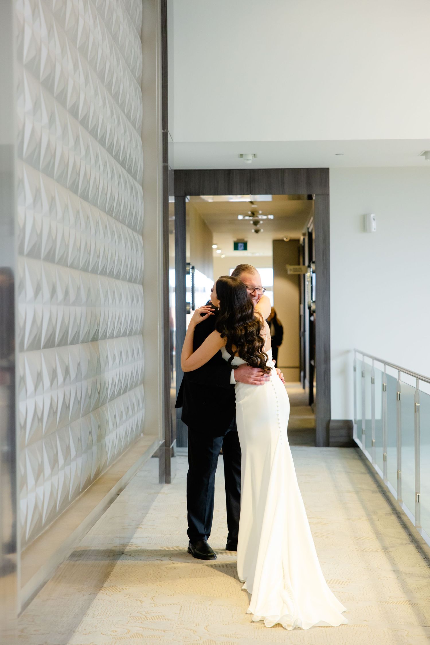 An intimate embrace between a couple in a sleek modern hallway.