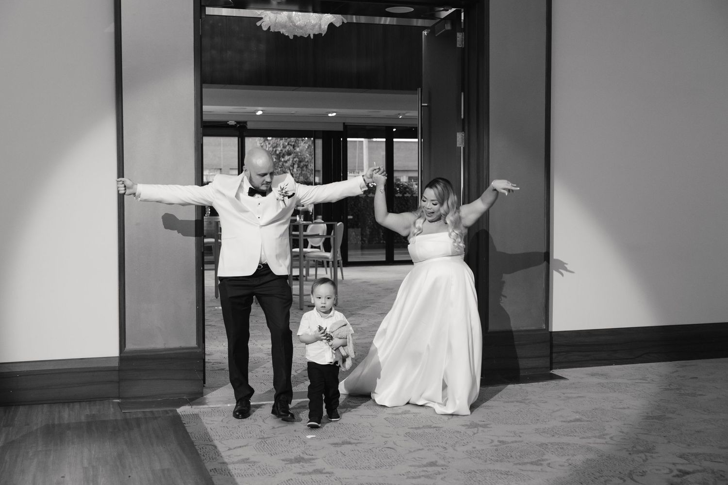 Black and white wedding celebration photo in modern venue hallway.
