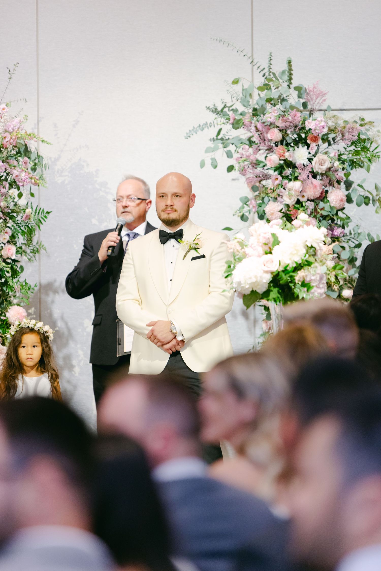 A wedding ceremony with beautiful pink and white floral arrangements decorating the altar area.