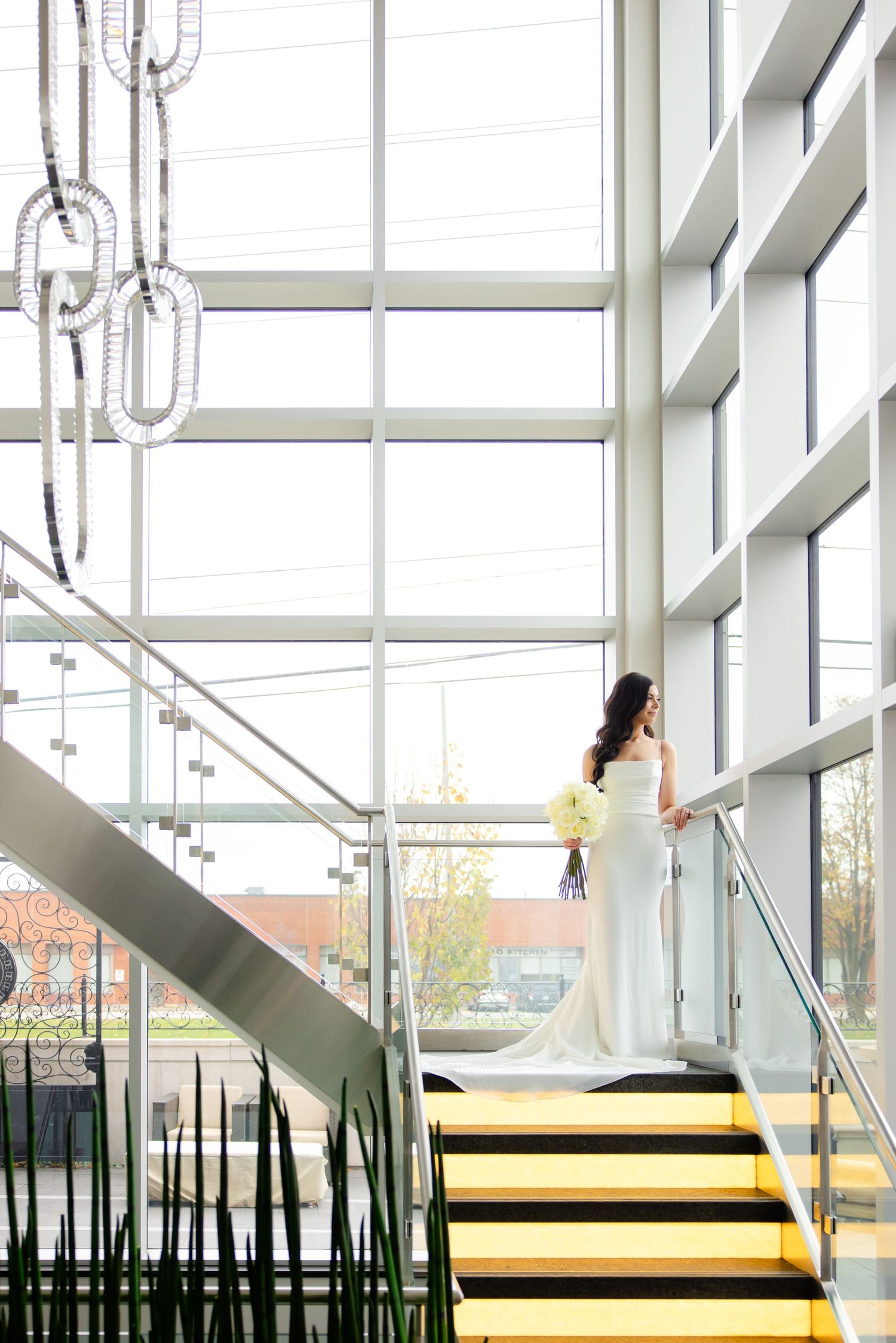 Elegant silhouette on yellow stairs with dramatic window lighting and hanging geometric light fixtures.