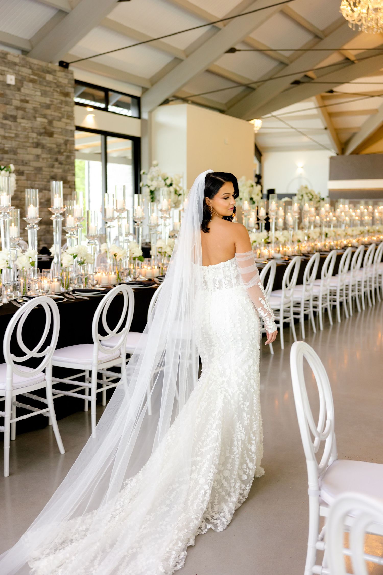 A bridal gown with flowing train photographed in an elegant reception venue with modern decor.