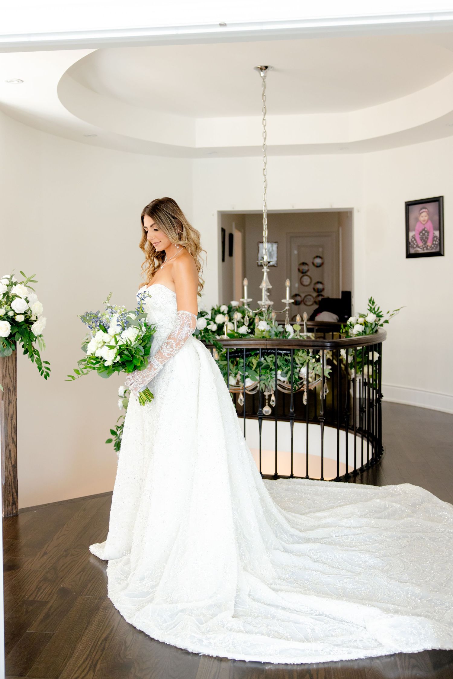 Elegant bridal portrait featuring long train wedding dress and white floral bouquet.
